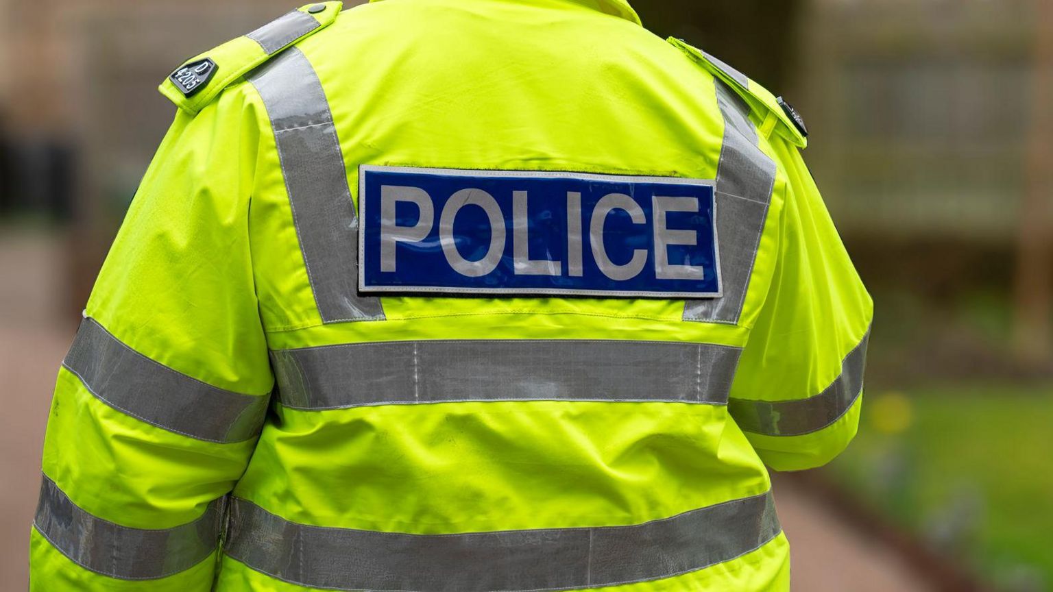 Stock image of a police officer in hi-vis uniform walking away from camera