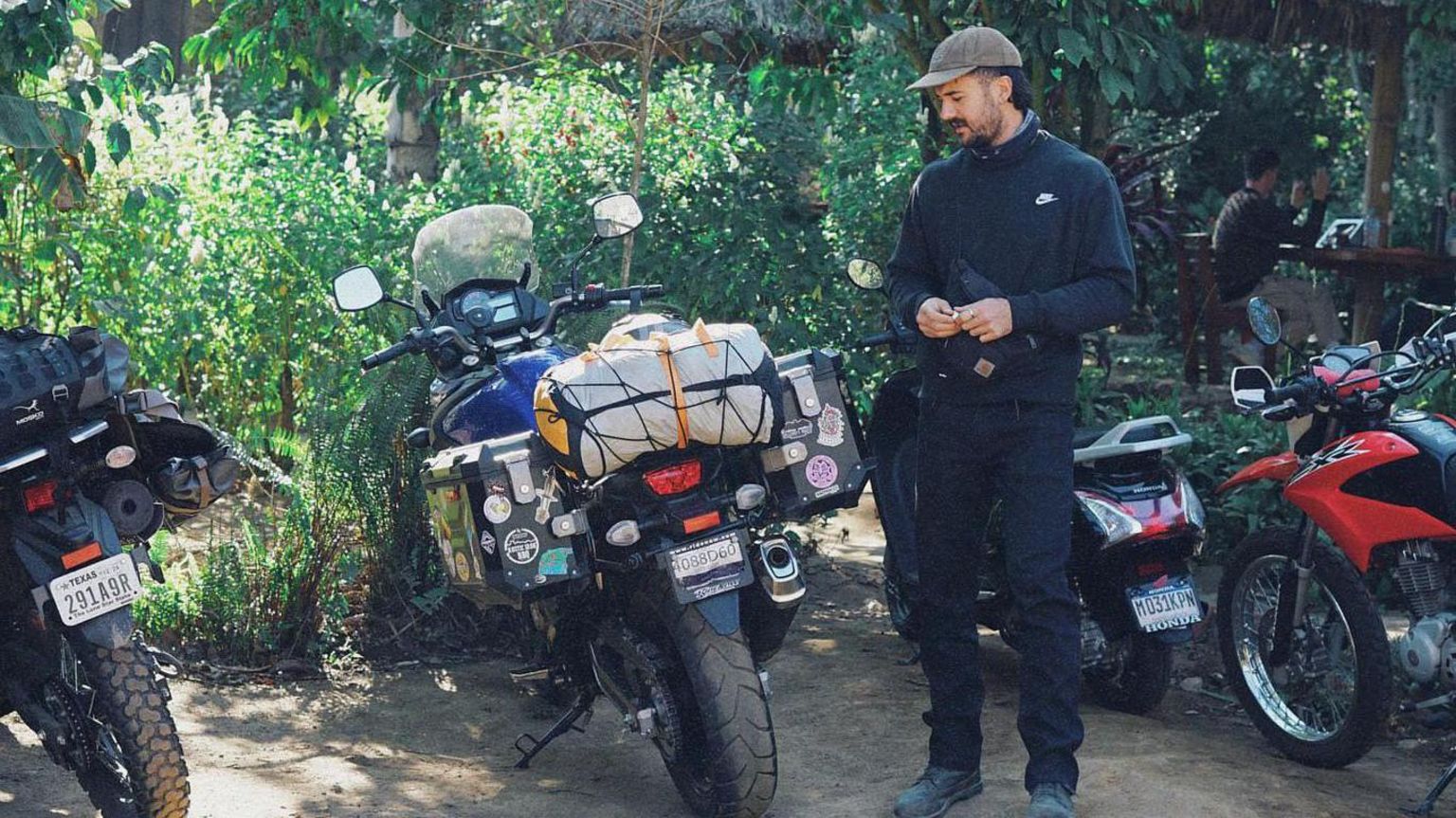 Luke Tarrant on an adventure standing by motorbikes