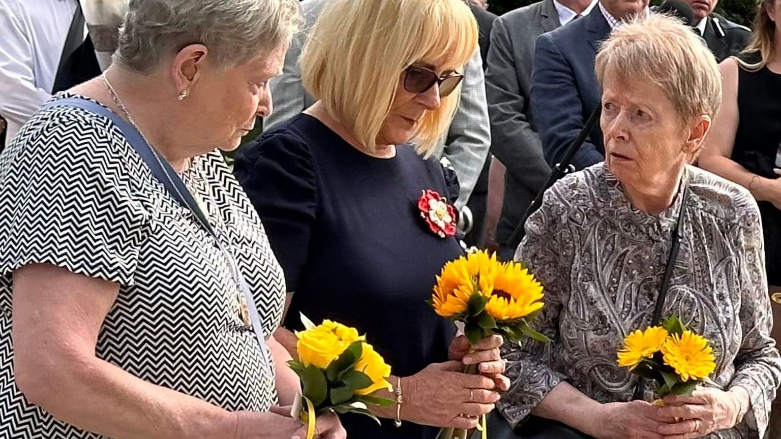The mothers of Forbury gardens victims holding yellow sunflowers