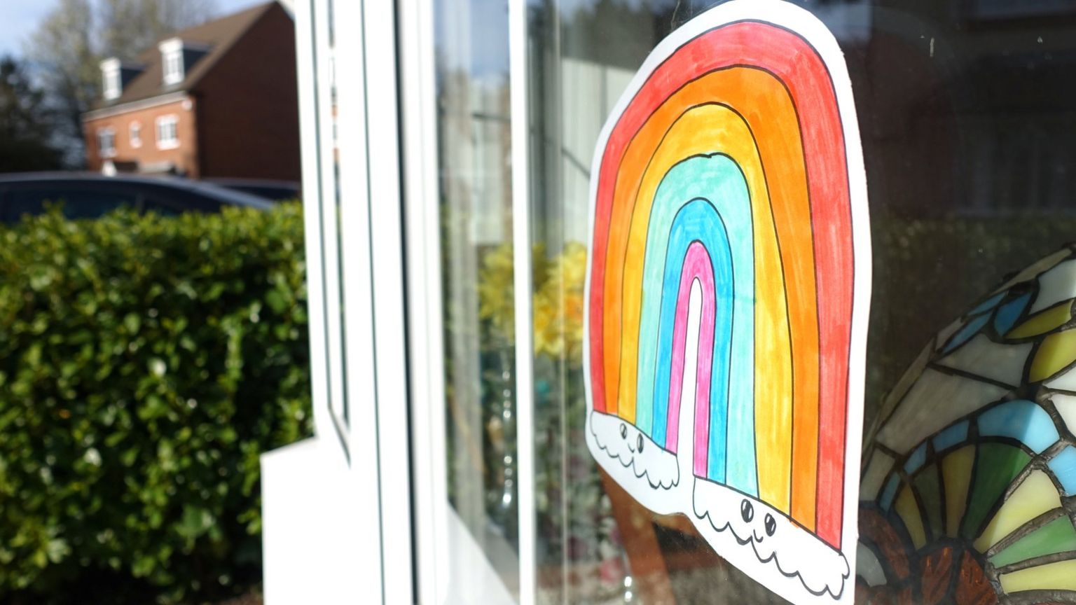 A picture of a rainbow is seen in a window