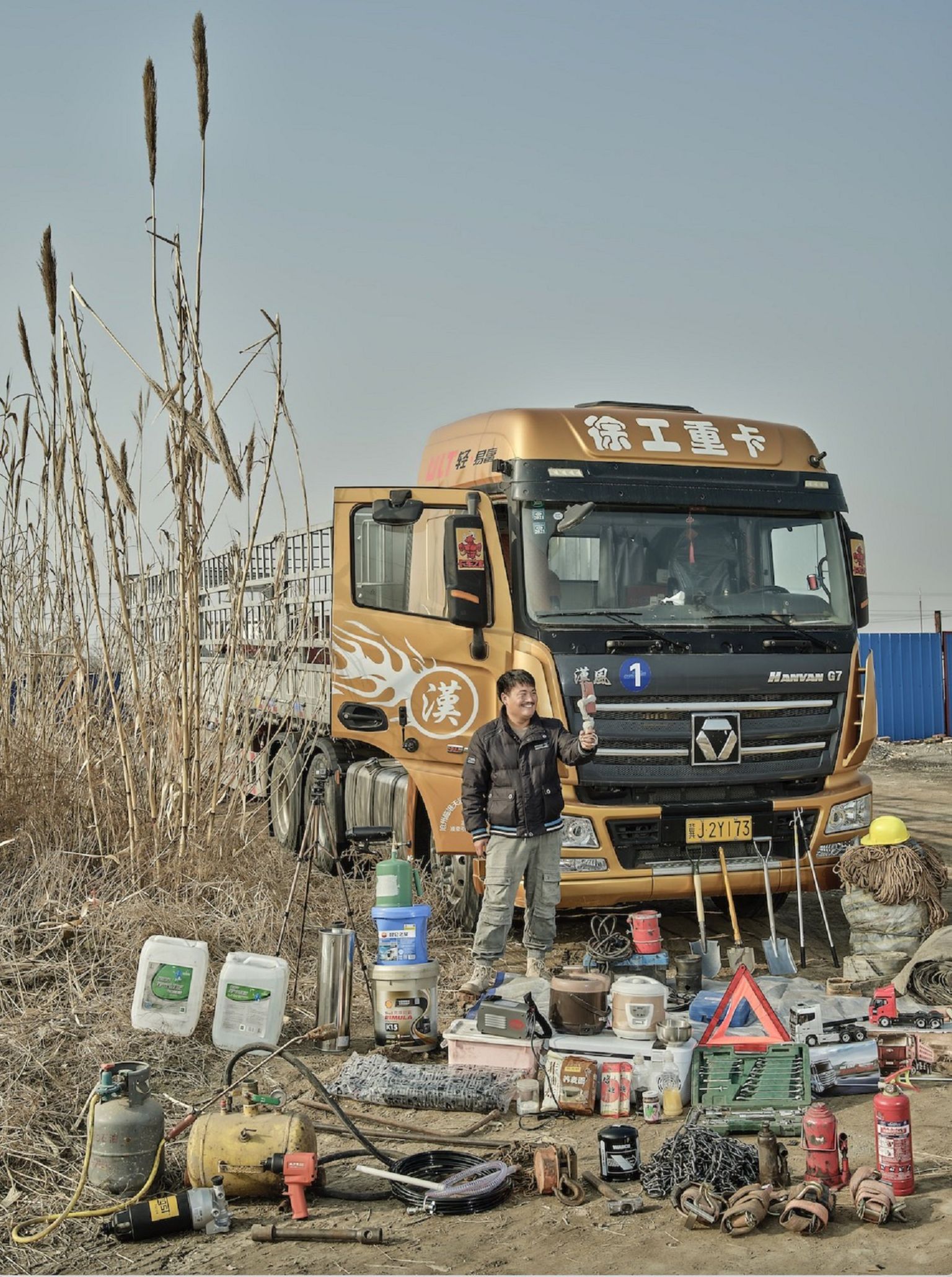 Мужчина делает селфи, стоя перед своим грузовиком, перед которым разложено оборудование и припасы