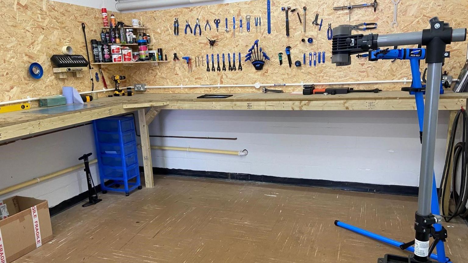 The photograph shows the interior of a workshop with lots of tools hanging on the walls and other pieces of equipment on the floor.