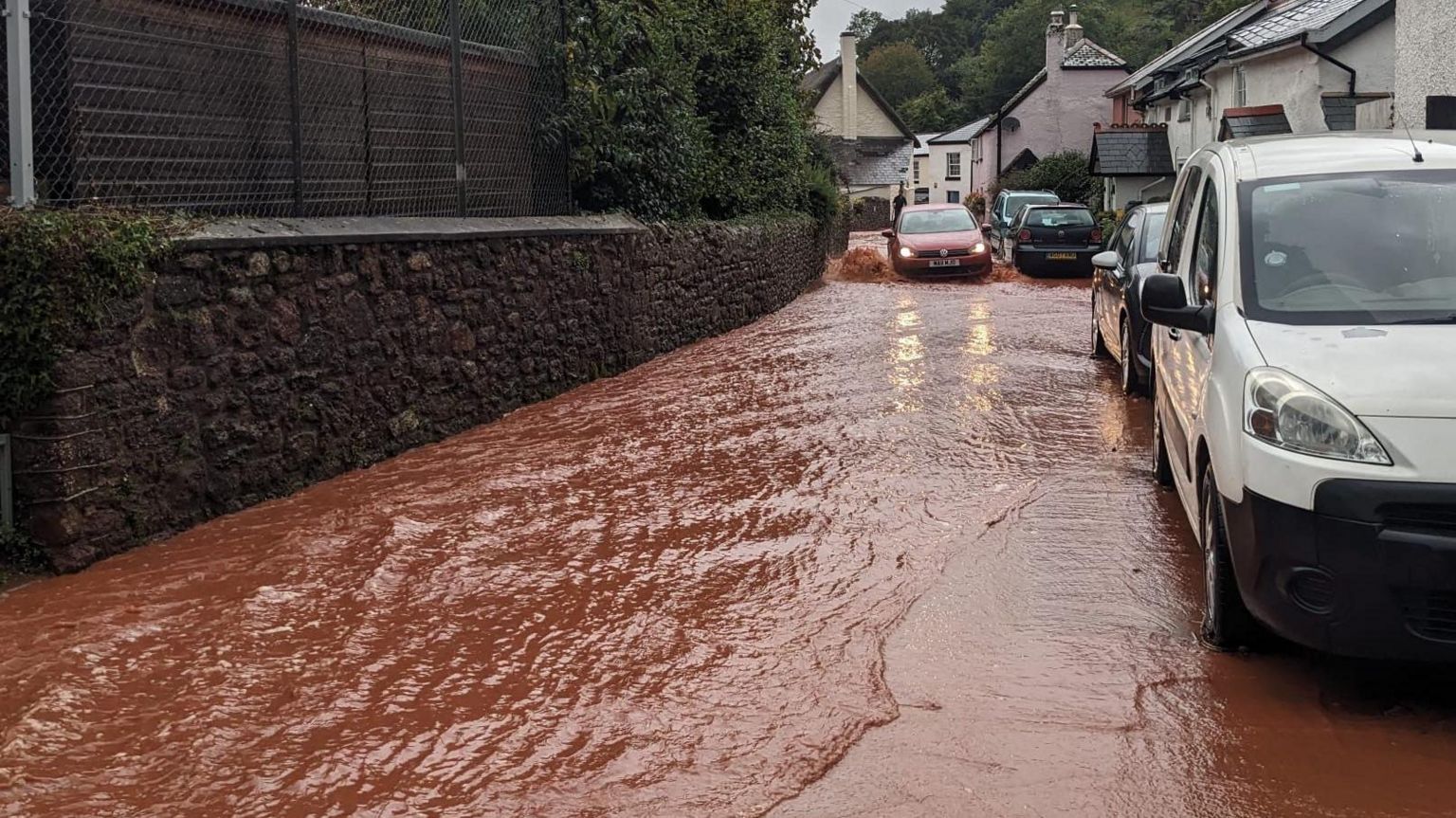  A car driving through flood water on a village road 