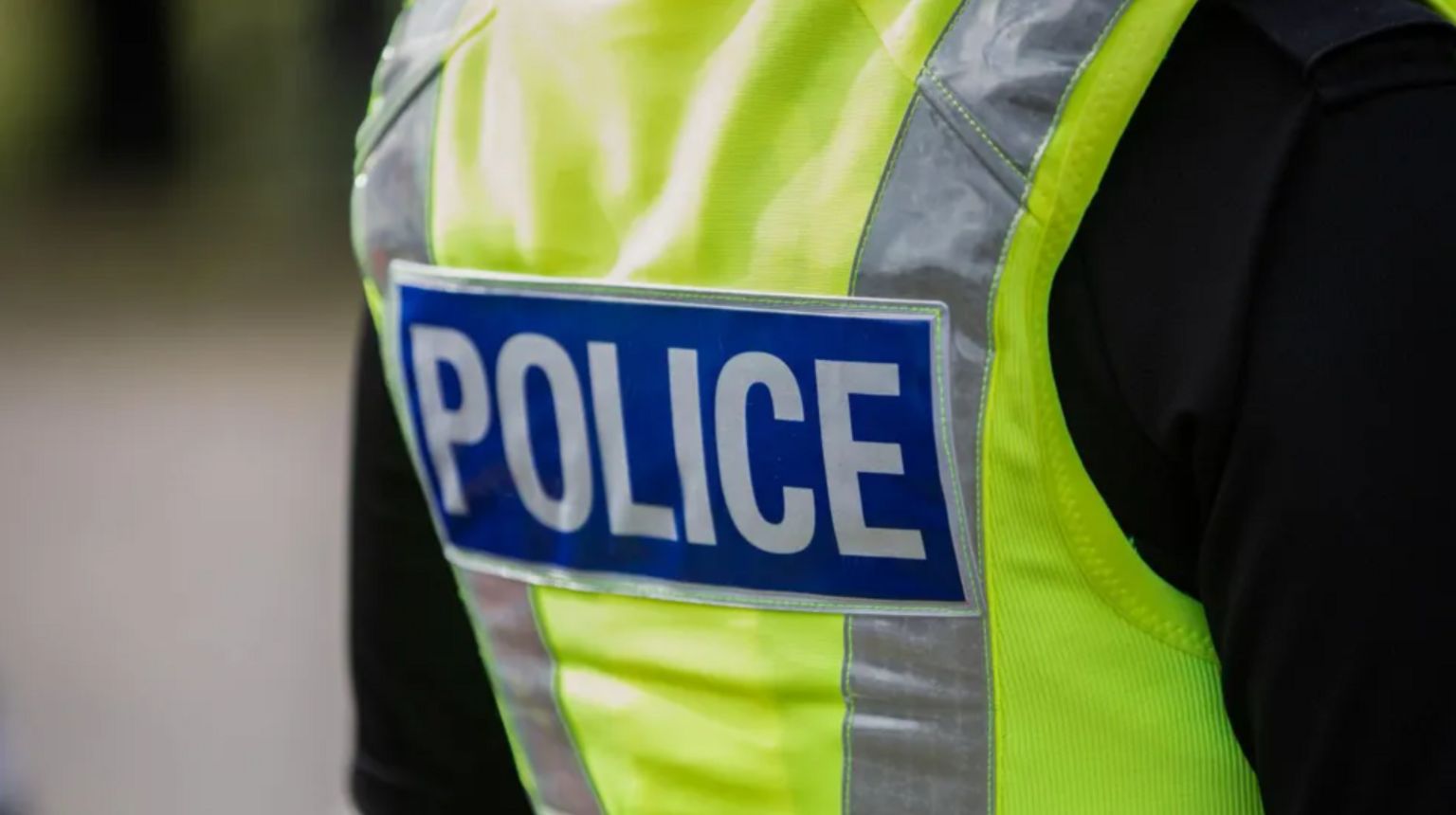 The back of a police officer's yellow jacket with the word police on it