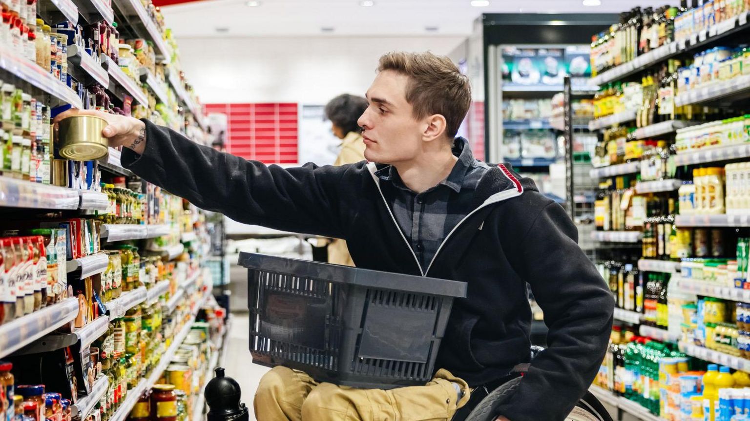 Person in wheelchair shopping and looking at prices in supermarket