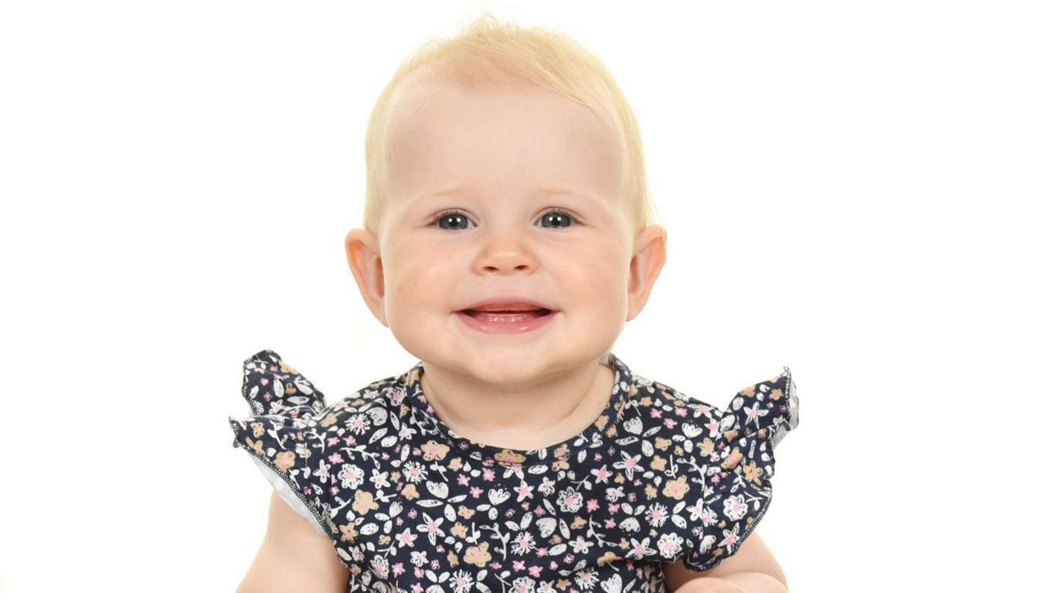 A blond baby smiling at the camera 