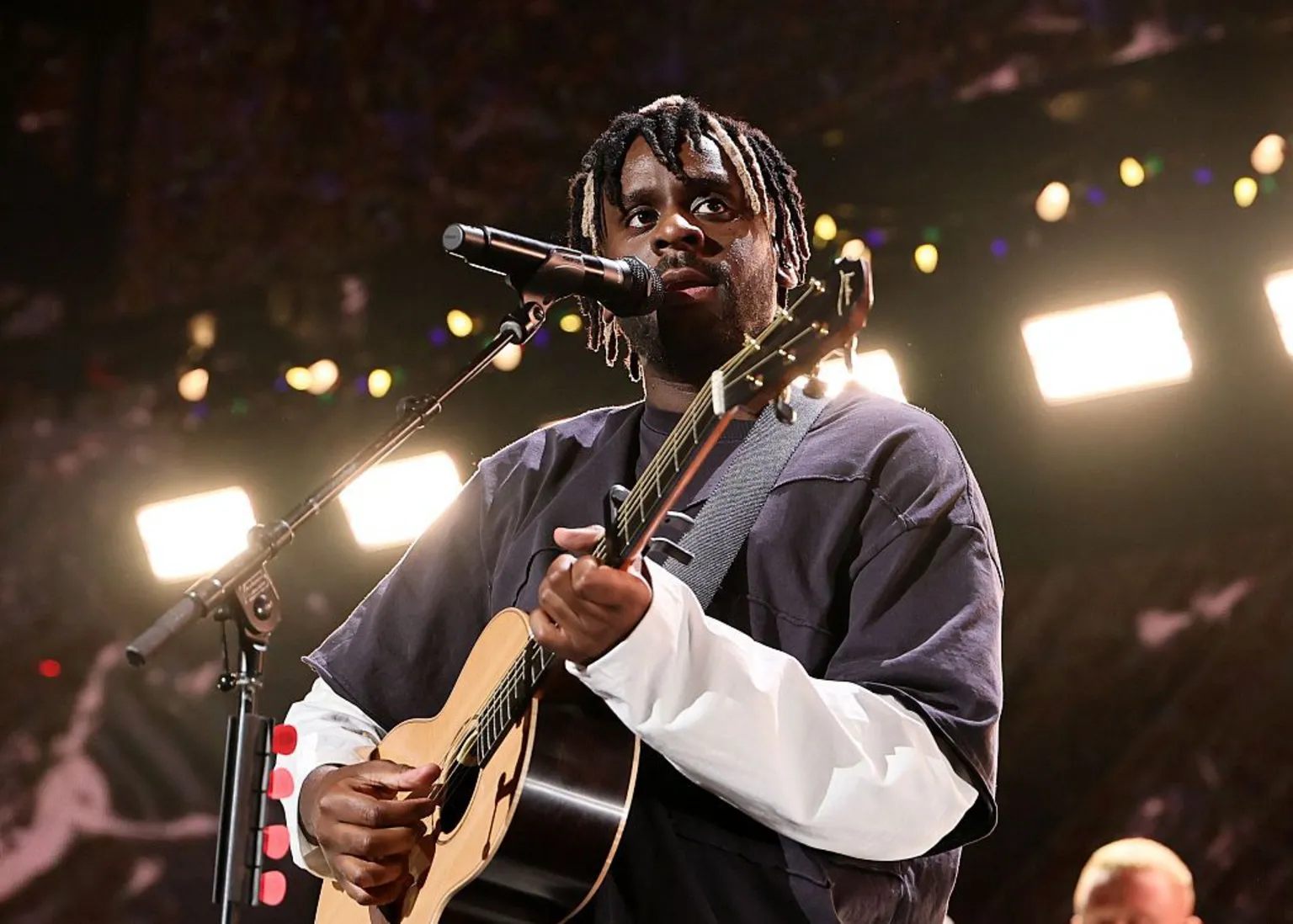 Getty Images Myles Smith performs onstage during iHeartRadio z100's Jingle Ball 2025 in New York City. He holds his guitar while singing pensively.