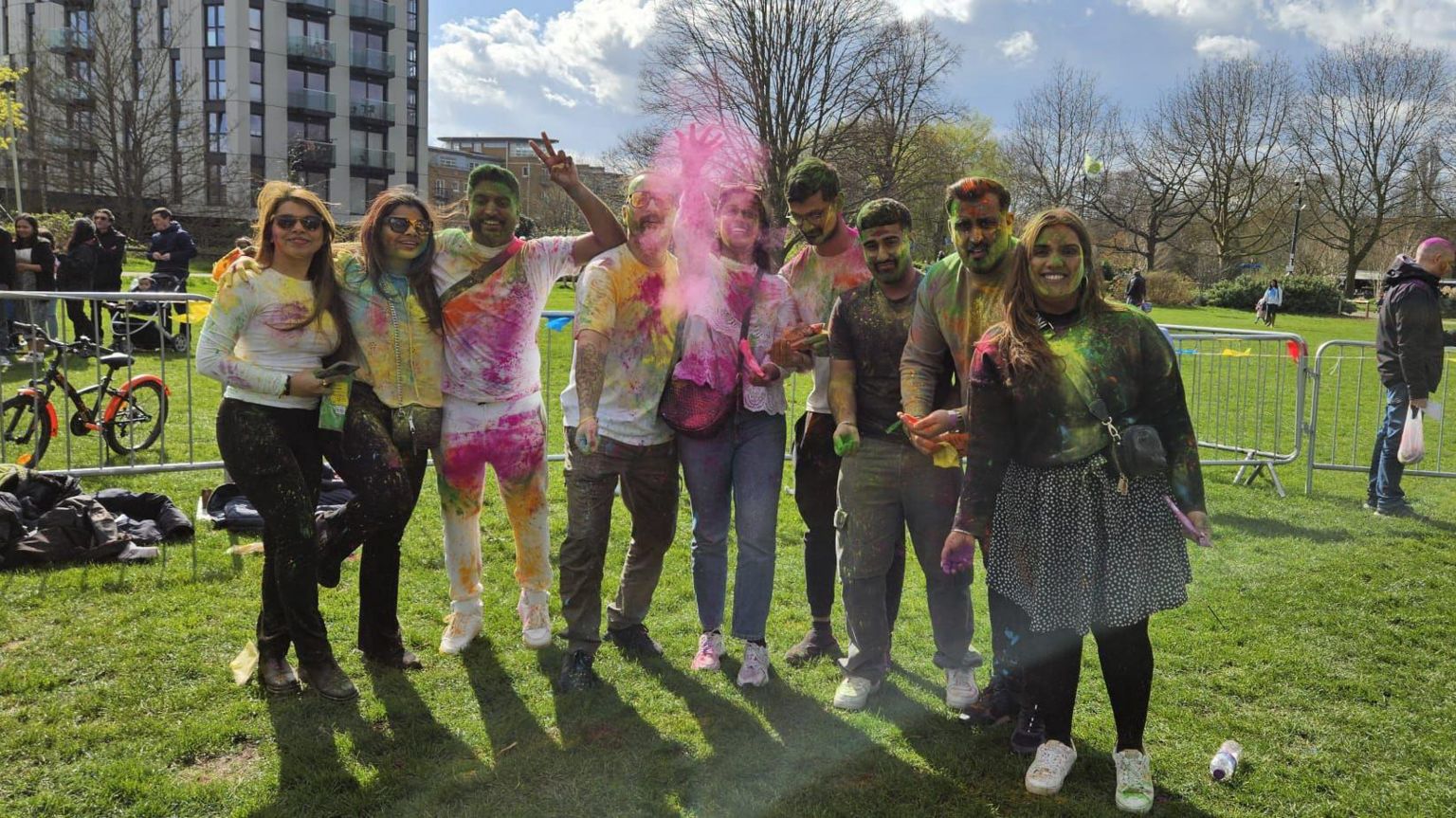 A group of people covered in powdered colour while playing Holi in central park in Chelmsford in Essex 