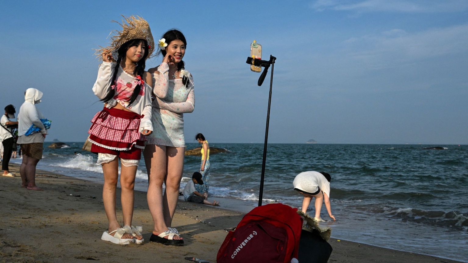 福建厦门某海滩上两位年轻女子以脚架竖起手机拍摄影片（24/5/2026）