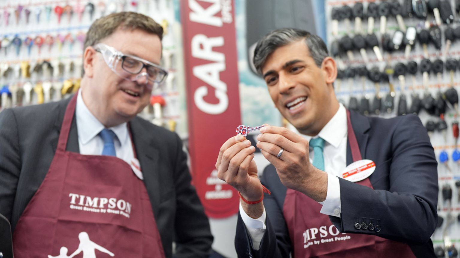 Rishi Sunak and Mel Stride look at a key during a visit to Timpsons