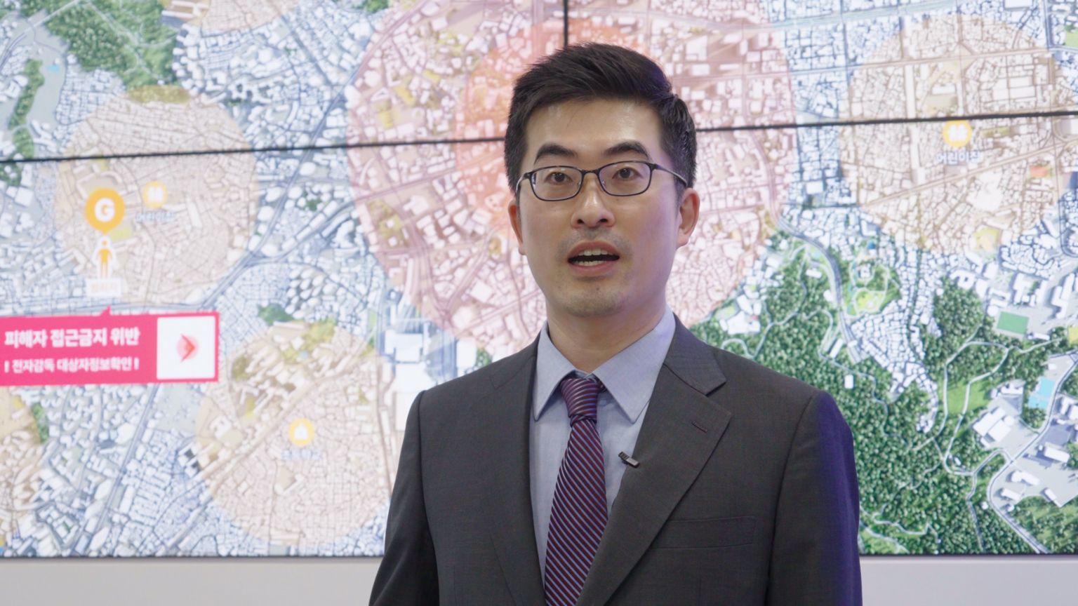 中央电子监控中心主任林合格站在一幅标示有圆形区域的大型空拍地图前。