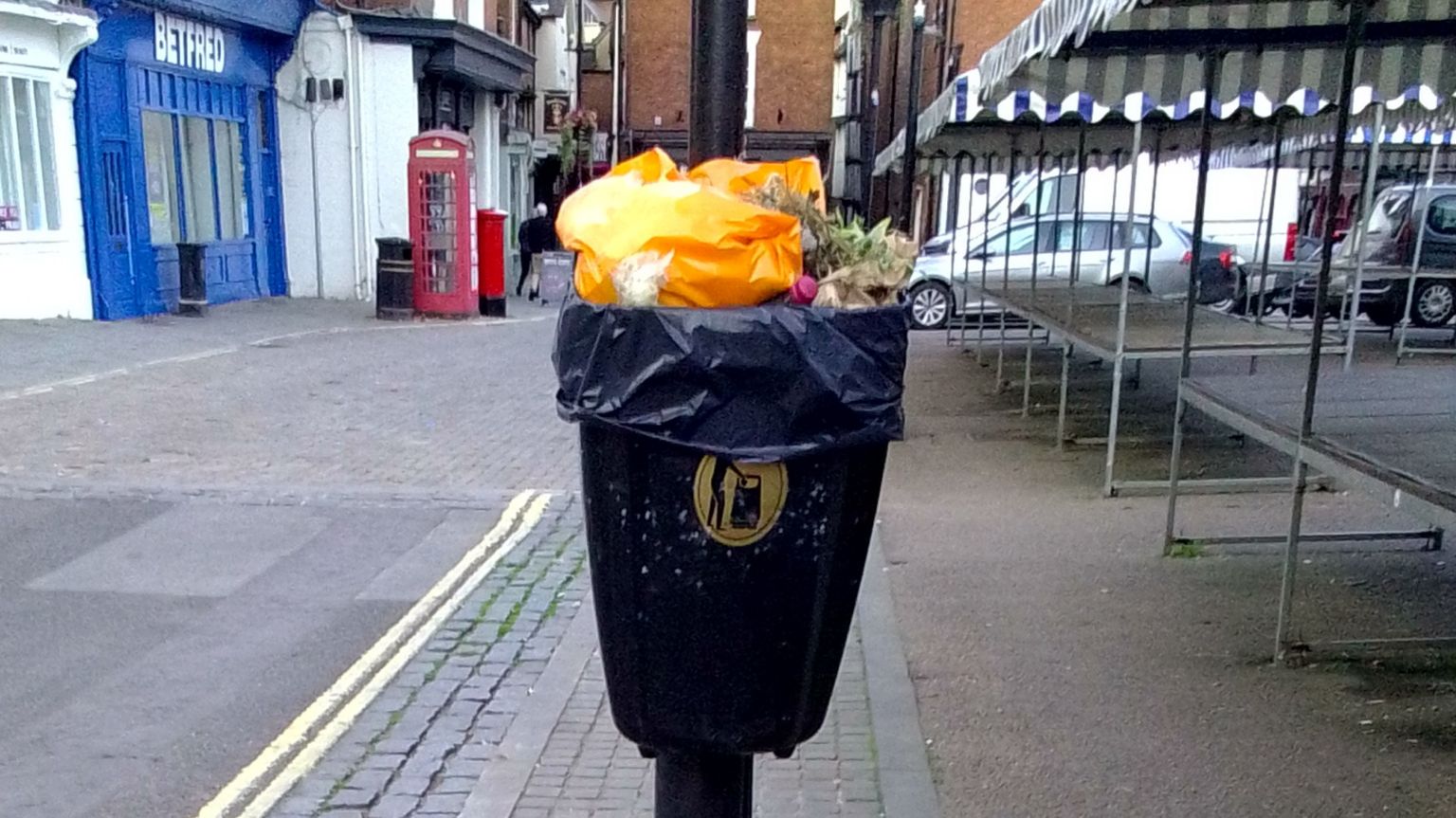 A bin in a street in Ludlow with rubbish piled right to the top