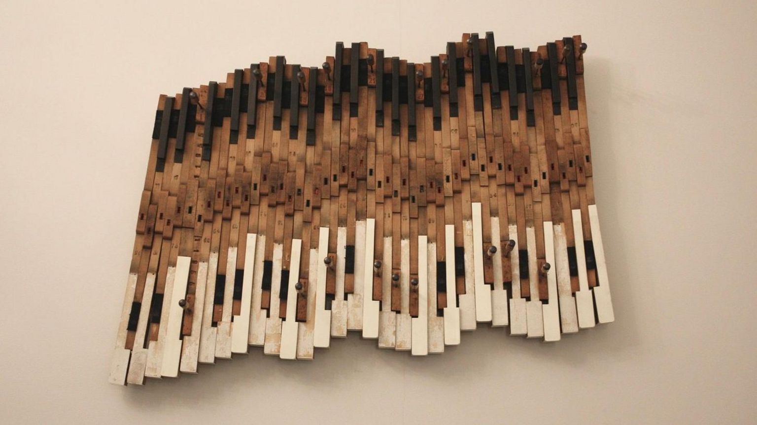 A piece of colourful wall art made using piano keys