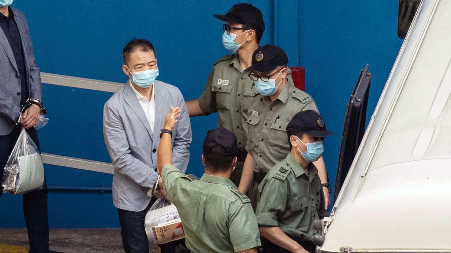 胡志伟（左，灰色外套者）被锁上手铐，由惩教署狱警押送上囚车送往西九龙裁判法院受审（8/7/2021）