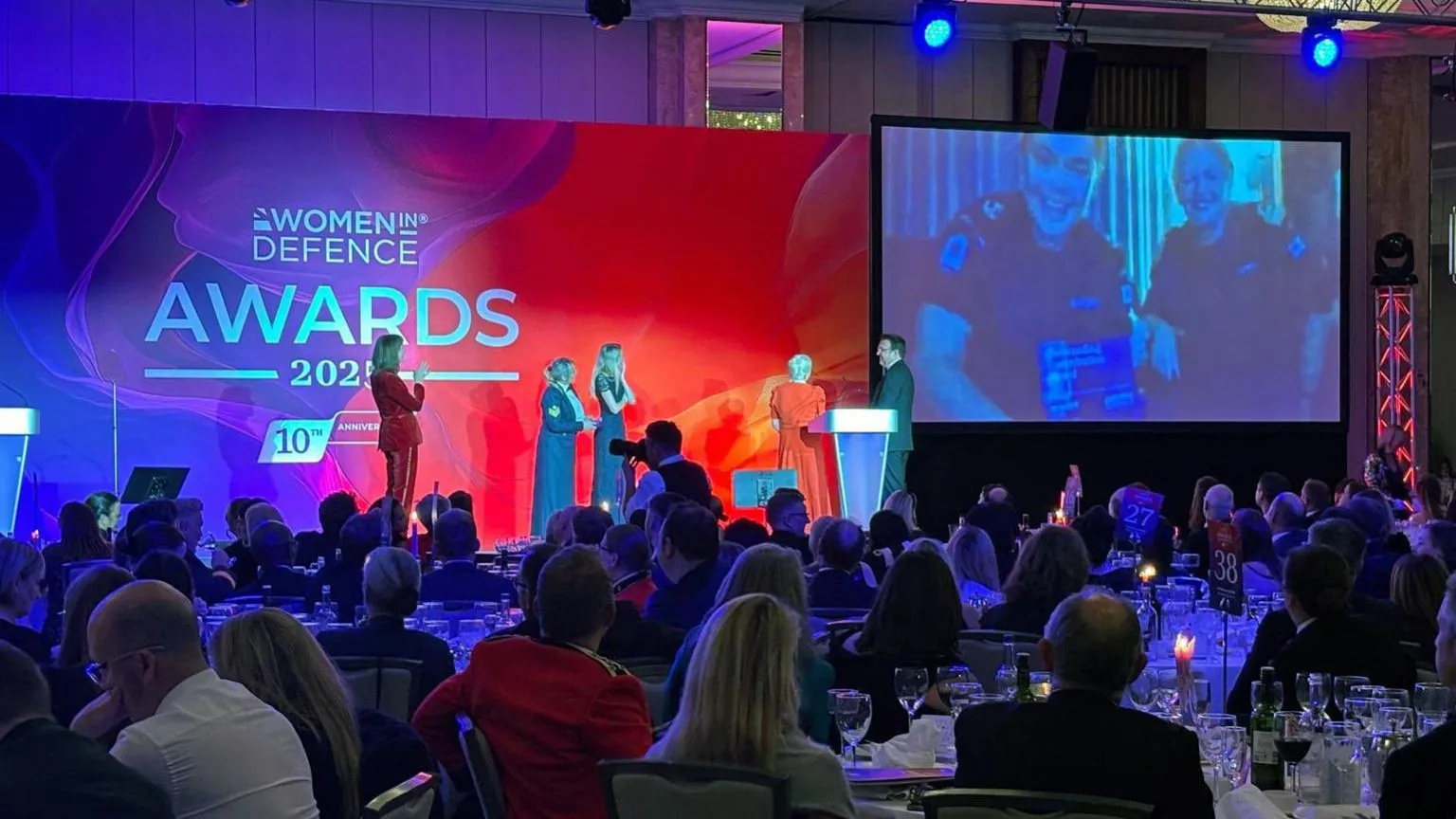 Royal Navy Wide shot of 2025 Women in Defence Awards ceremony showing crowd and stage, with a surprised Abigail Wright visible on a large screen