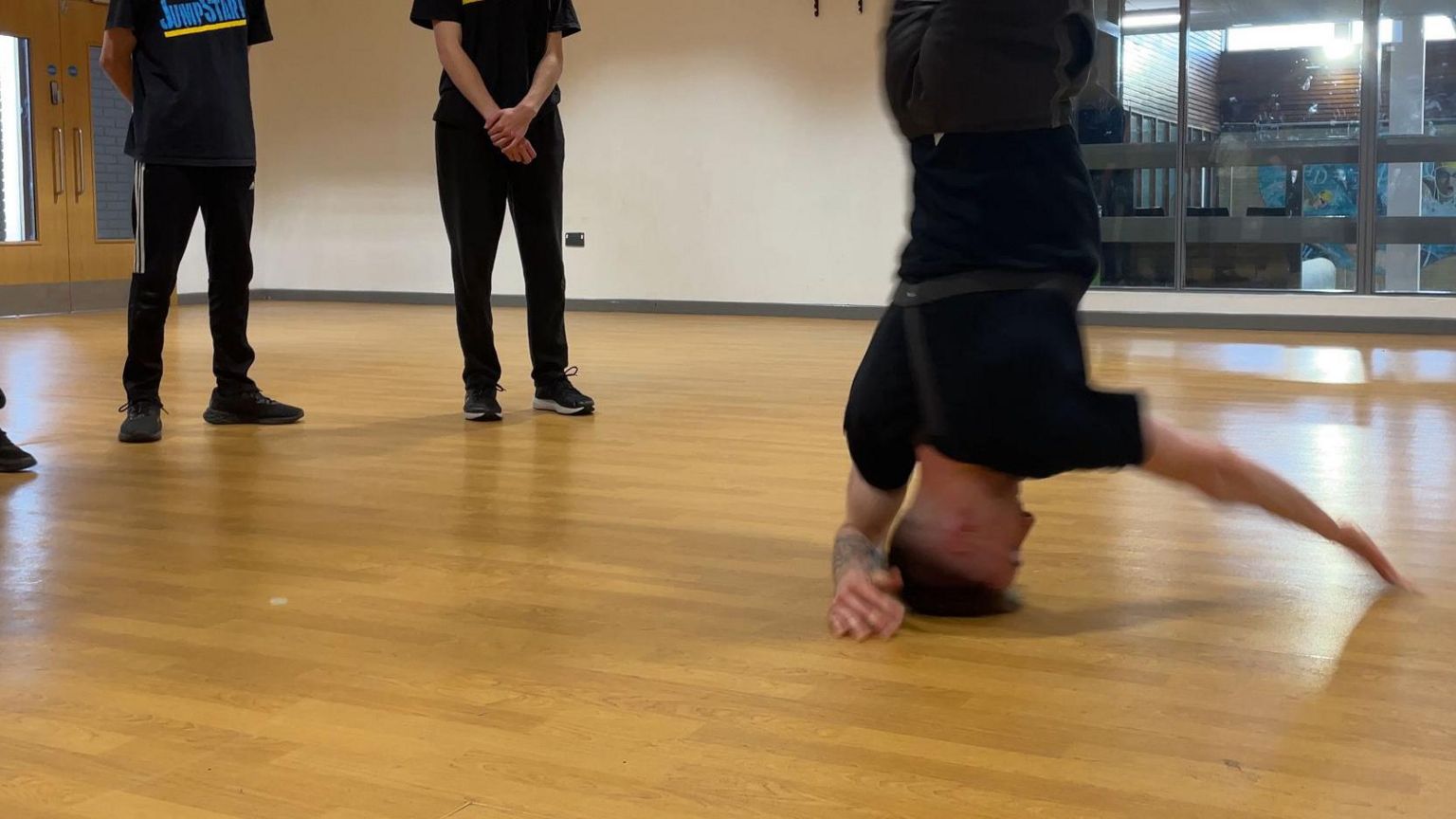 A dancer spinning on their head in a dance studio