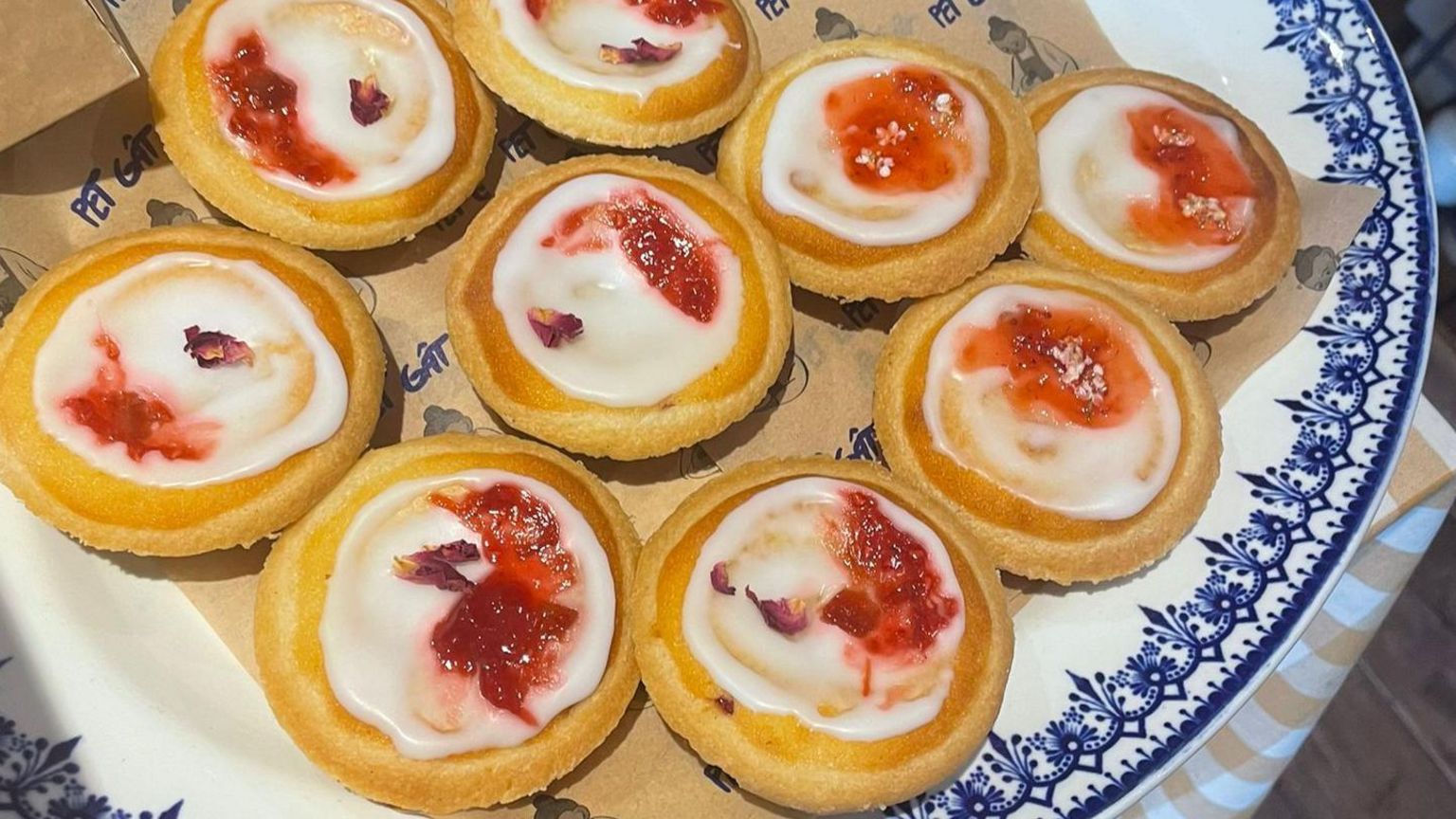 Iced tarts with a red jam finish on a blue and white ceramic plate