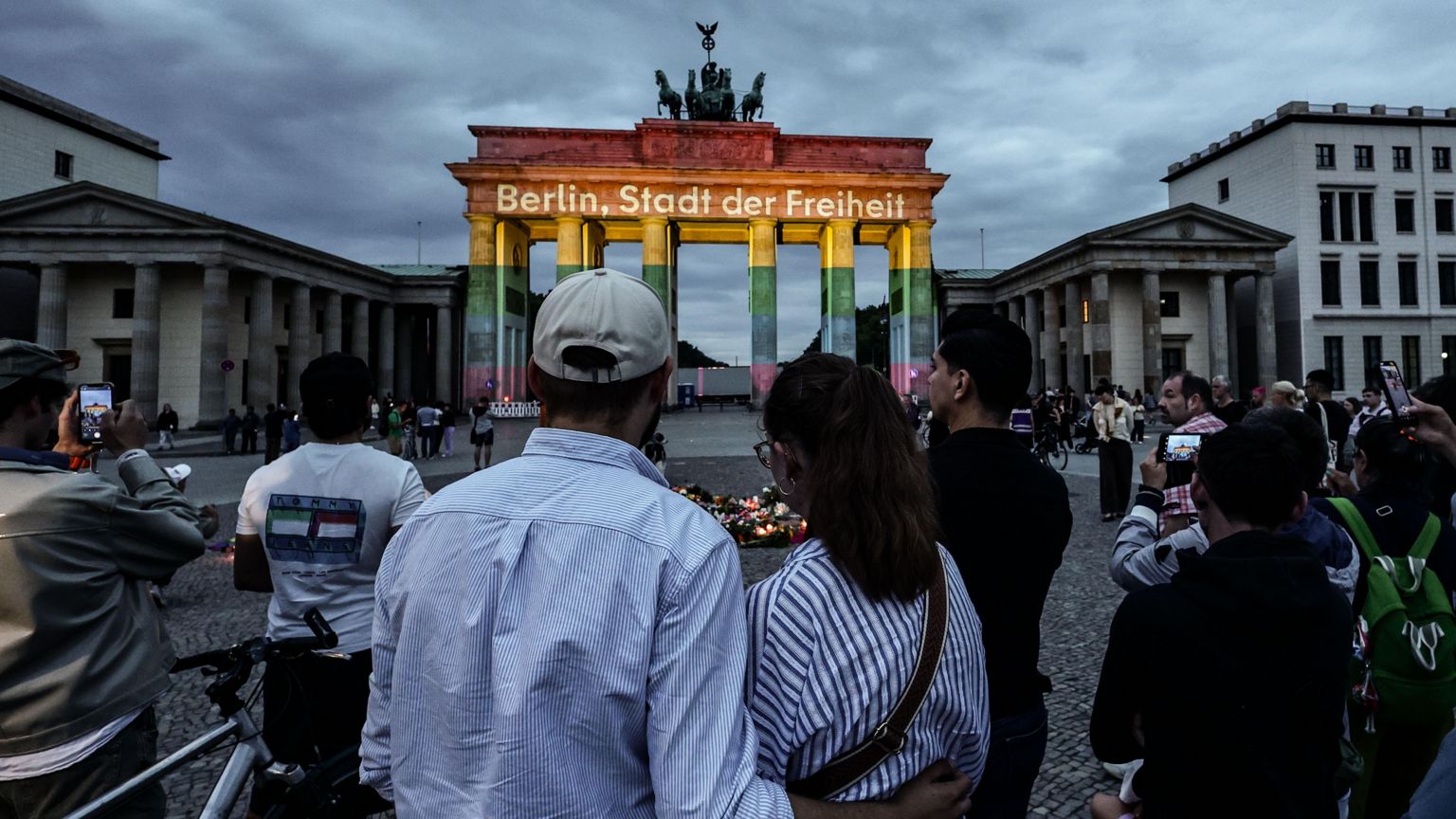 人们在勃兰登堡门前悼念，勃兰登堡门亮起“Berlin, city of freedom”讯息灯光。德国柏林2026年7月26日，在克里斯托弗街日（CSD）巡游路线旁一辆汽车冲入人群的事发地点附近。