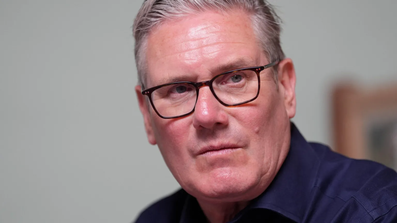 Reuters Sir Keir Starmer wearing glasses and a dark blue shirt looking serious