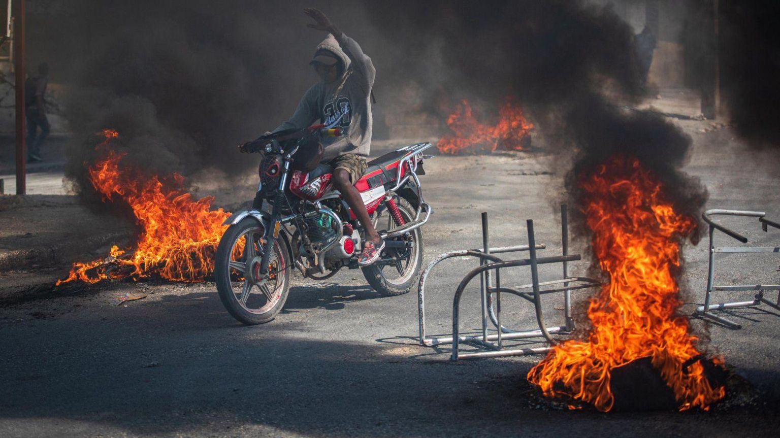 A man rides a motorcycle as tyres burn in Port-au-Prince, Haiti. Photo: March 2024
