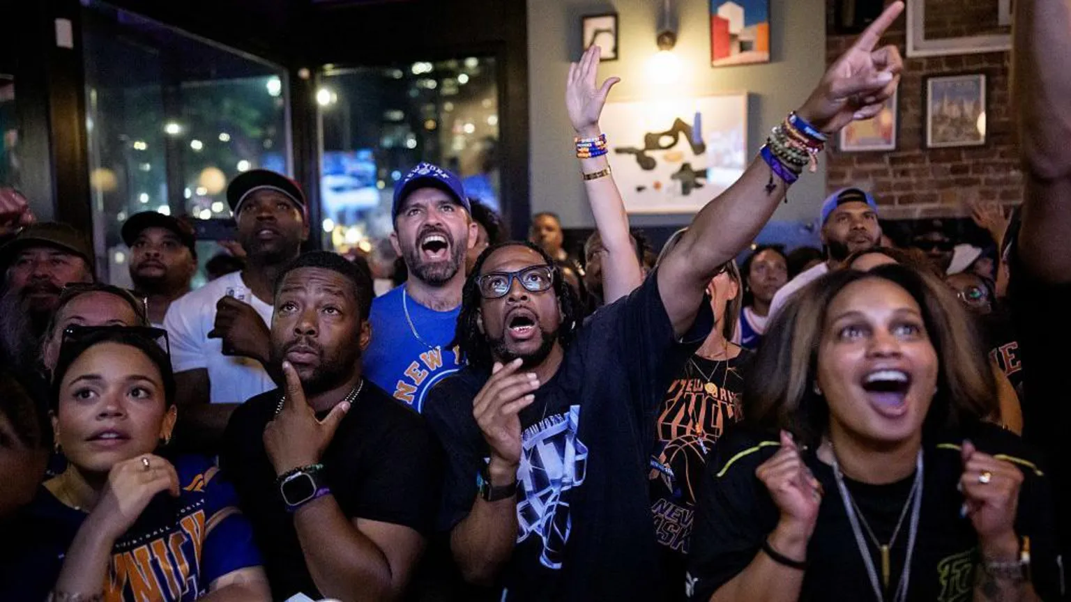 Getty Images A group of cheering fans wearing Knicks gear in a bar