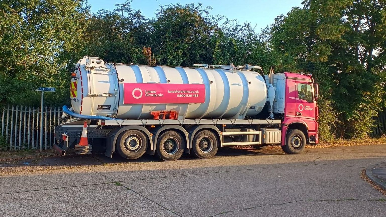 Side view of a pink and white sewage tanker