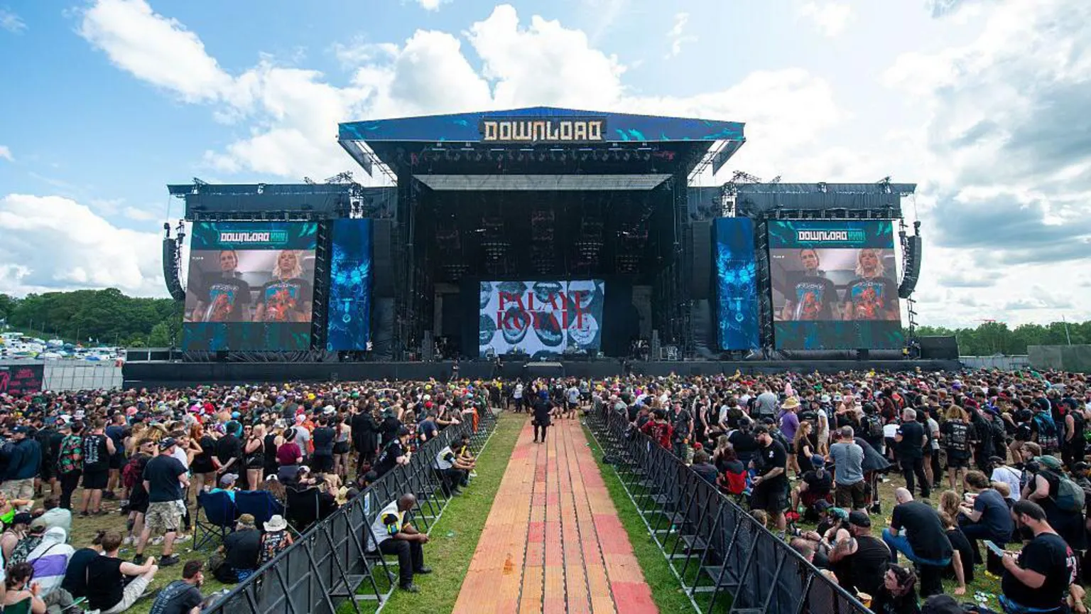Getty Images The main stage at Download Festival, the crowd is split down the middle. Crowds of people are watching the stage stood and sat on the grass.