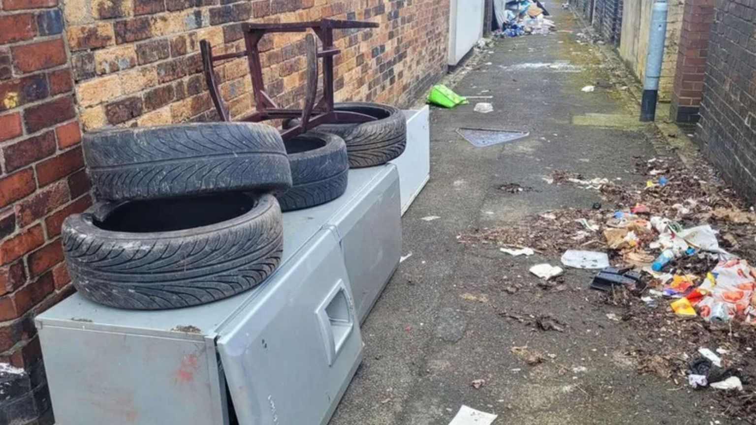 Dumped tyres and a fridge in an alley