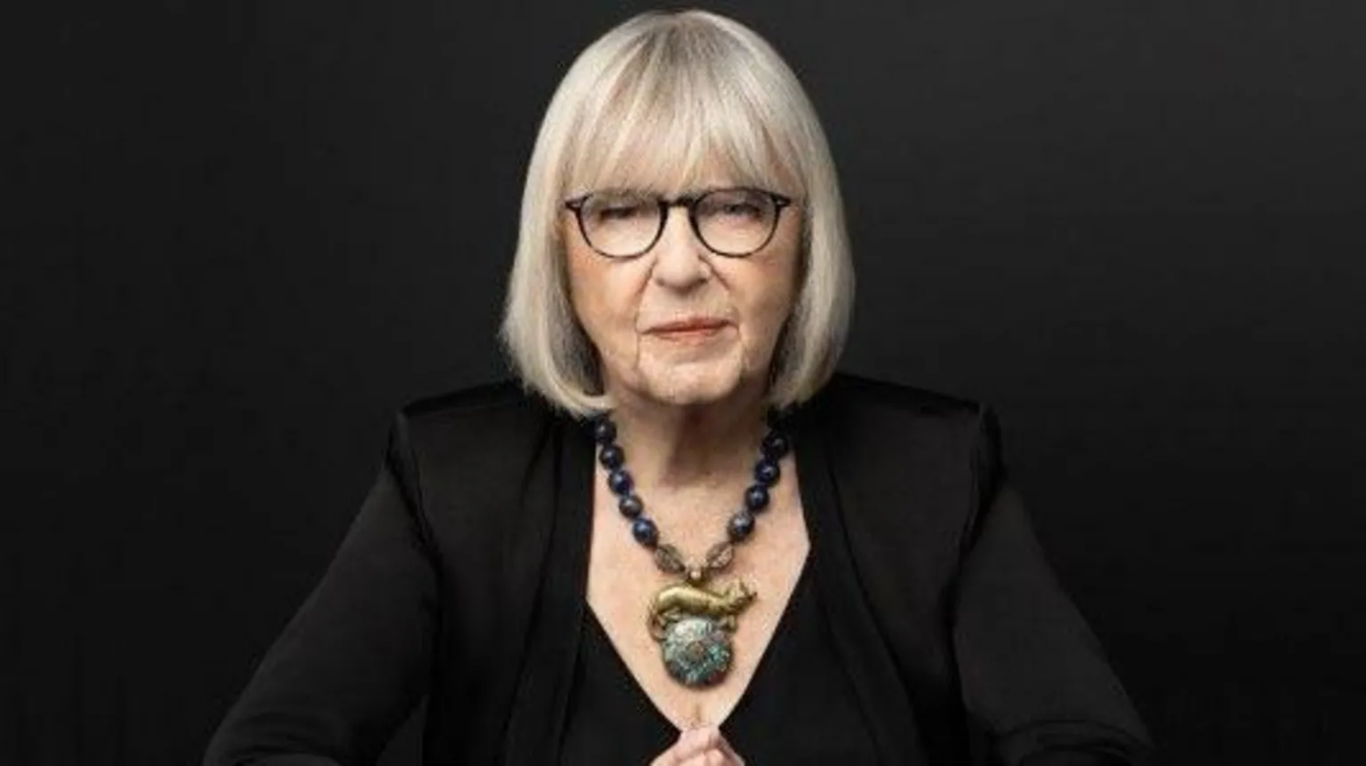 Beowulf Sheehan A professional headshot of Harriet Newman Cohen, where she wears a black top, large statement necklace. Her hair is cut in a silver bob