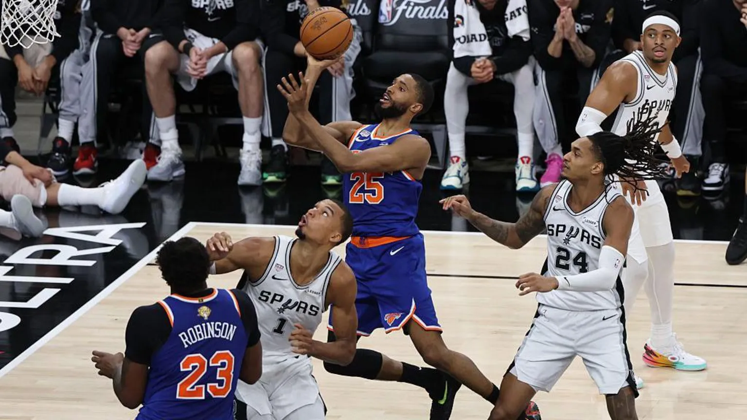 NBAE via Getty Images A Knicks player leaps towards the basket with the ball in hand as opposing Spurs players surround him