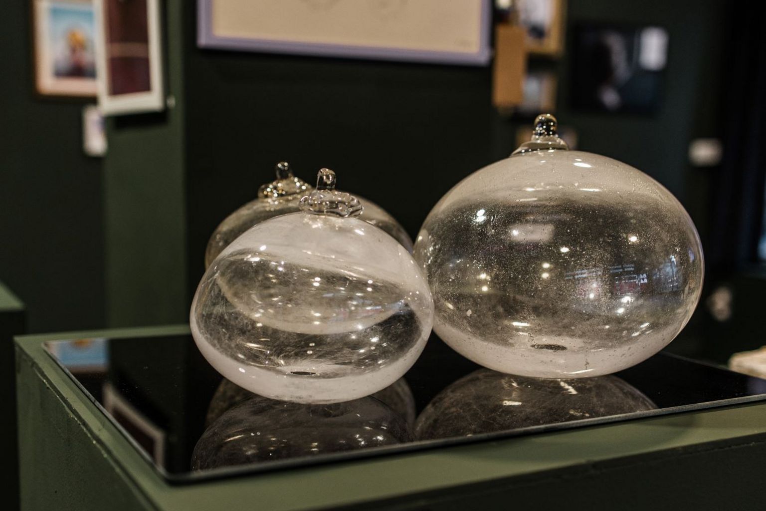 Three large glass representations of human breasts, transparent with a white tinge