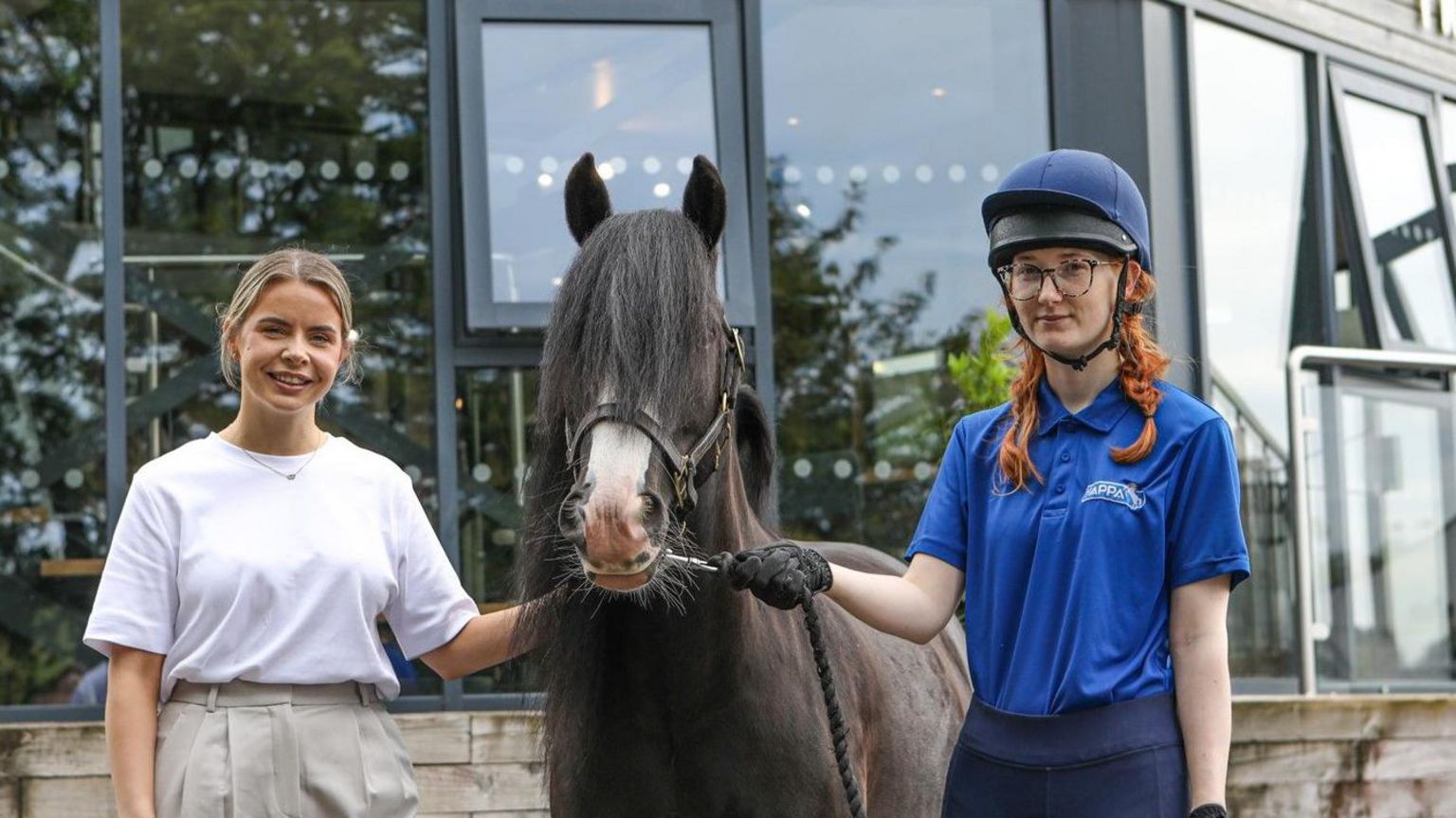 Amelia Stalton (left) and Daniella Whittaker in riding gear holding a horse named Espero (centre)