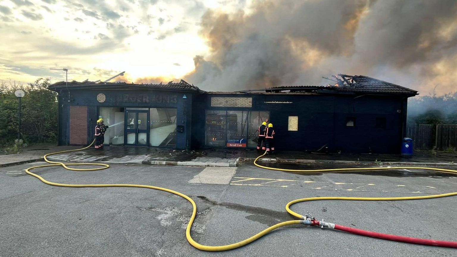 A burnt former burger king with a fire hose in the foreground 