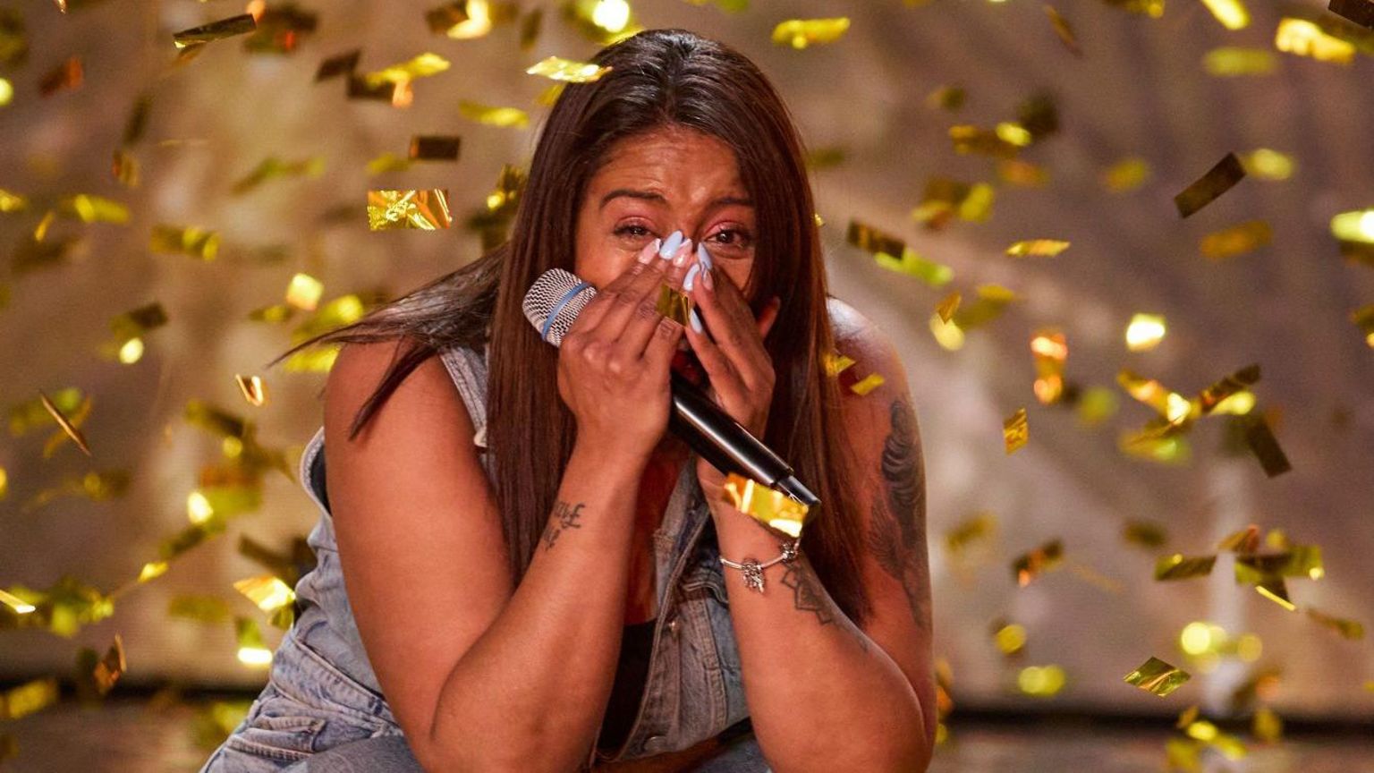 Taryn Charles holds her microphone on Britain's Got Talent and is surrounded by golden confetti