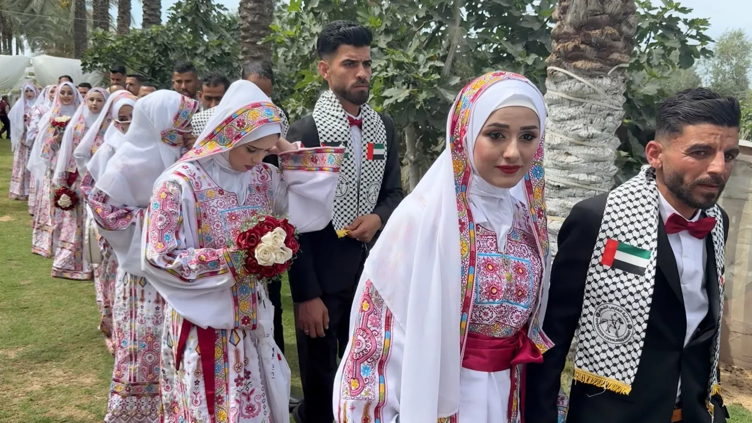 Couples in their wedding clothes walking in a line.