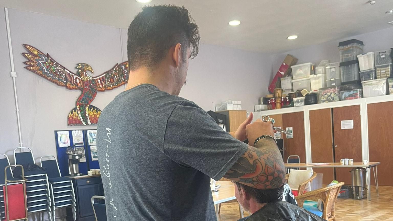 Eddie Ilic cutting a man's hair inside a hall