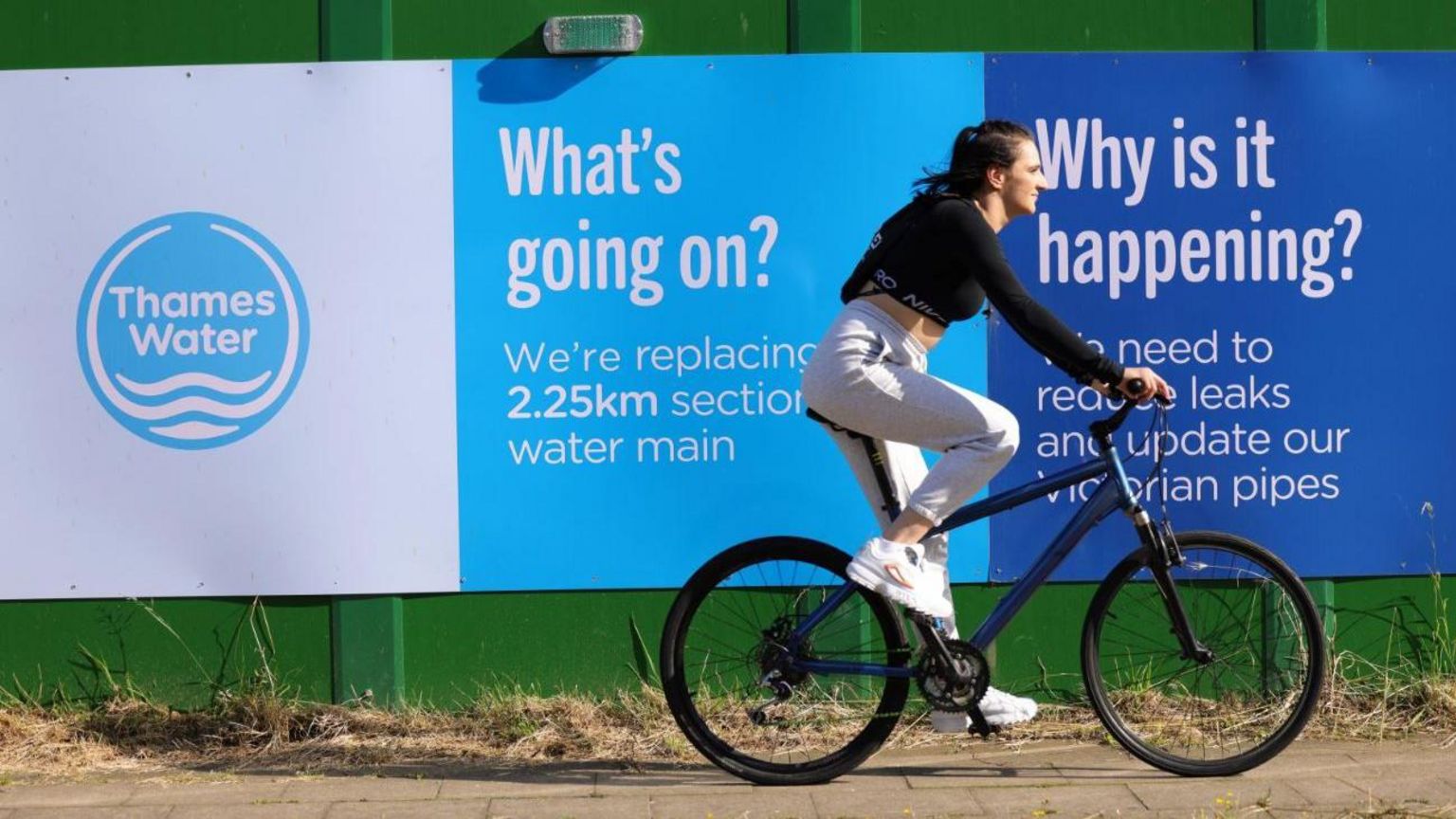 Image of a woman riding a bike passes a Thames Water construction site in London on 10 July