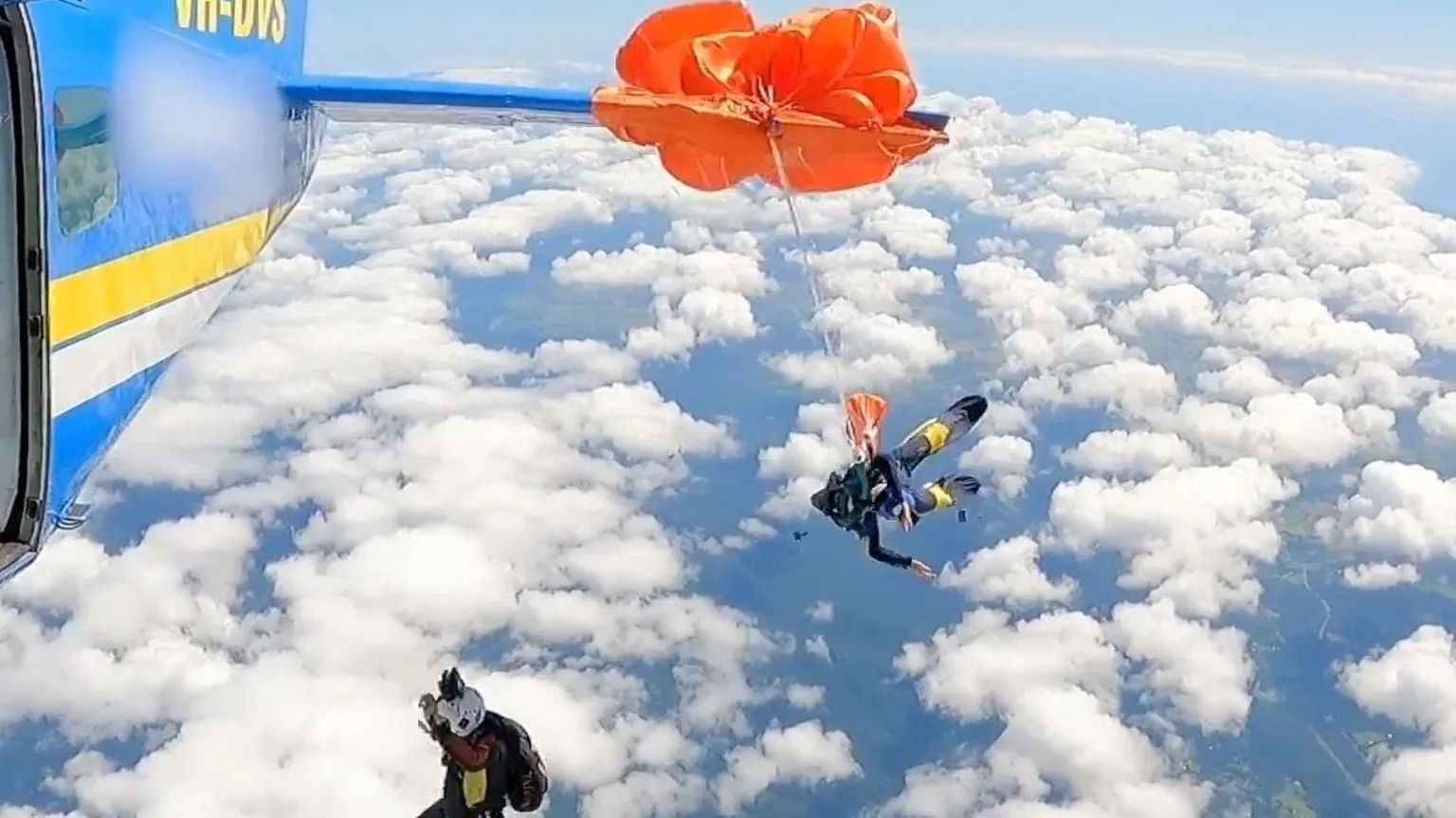 An orange parachute wrapped around the wing of a plane