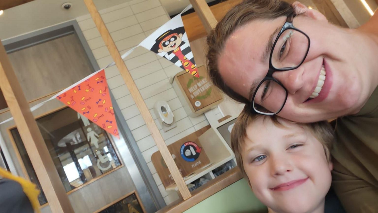 Stephanie takes a selfie with her young son Glen, both of whom are looking into the camera and smiling. Stephanie is wearing glasses, while Glen has short brown hair