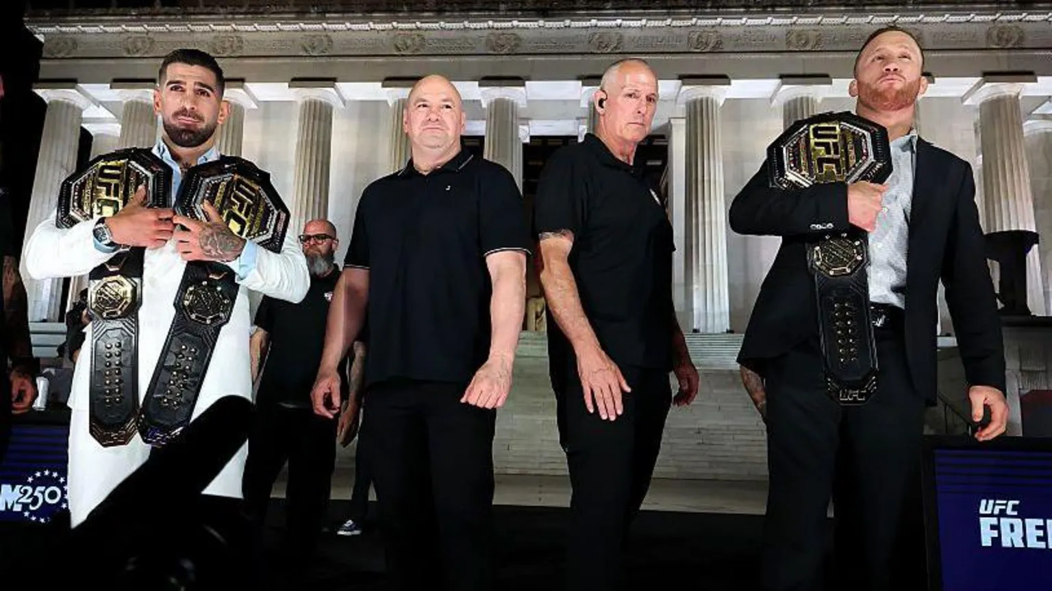 Zuffa LLC via Getty Images Two fighters holding UFC belts standing beside others in front of the Lincoln Memorial