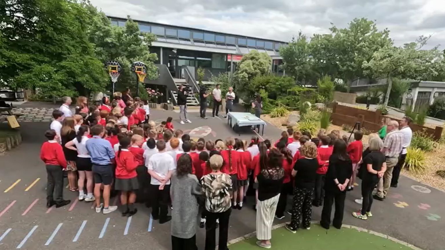 A group of Pokesdown Primary School children and teachers standing in a semi-circle around Mr Ball receiving his award