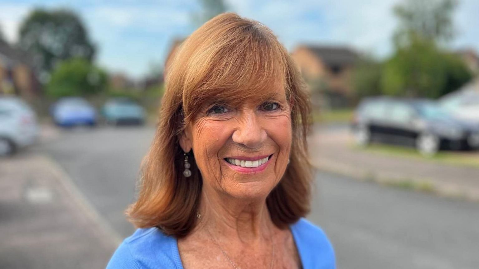 Olivia Izzard with shoulder-length ginger hair and a blue shirt