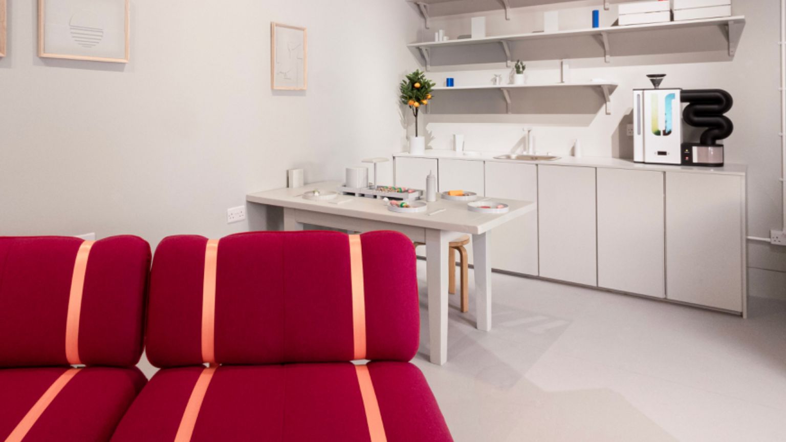 The exhibition's Innovo Room of the Future, a white room with white kitchen units, a white table and a bright red sofa