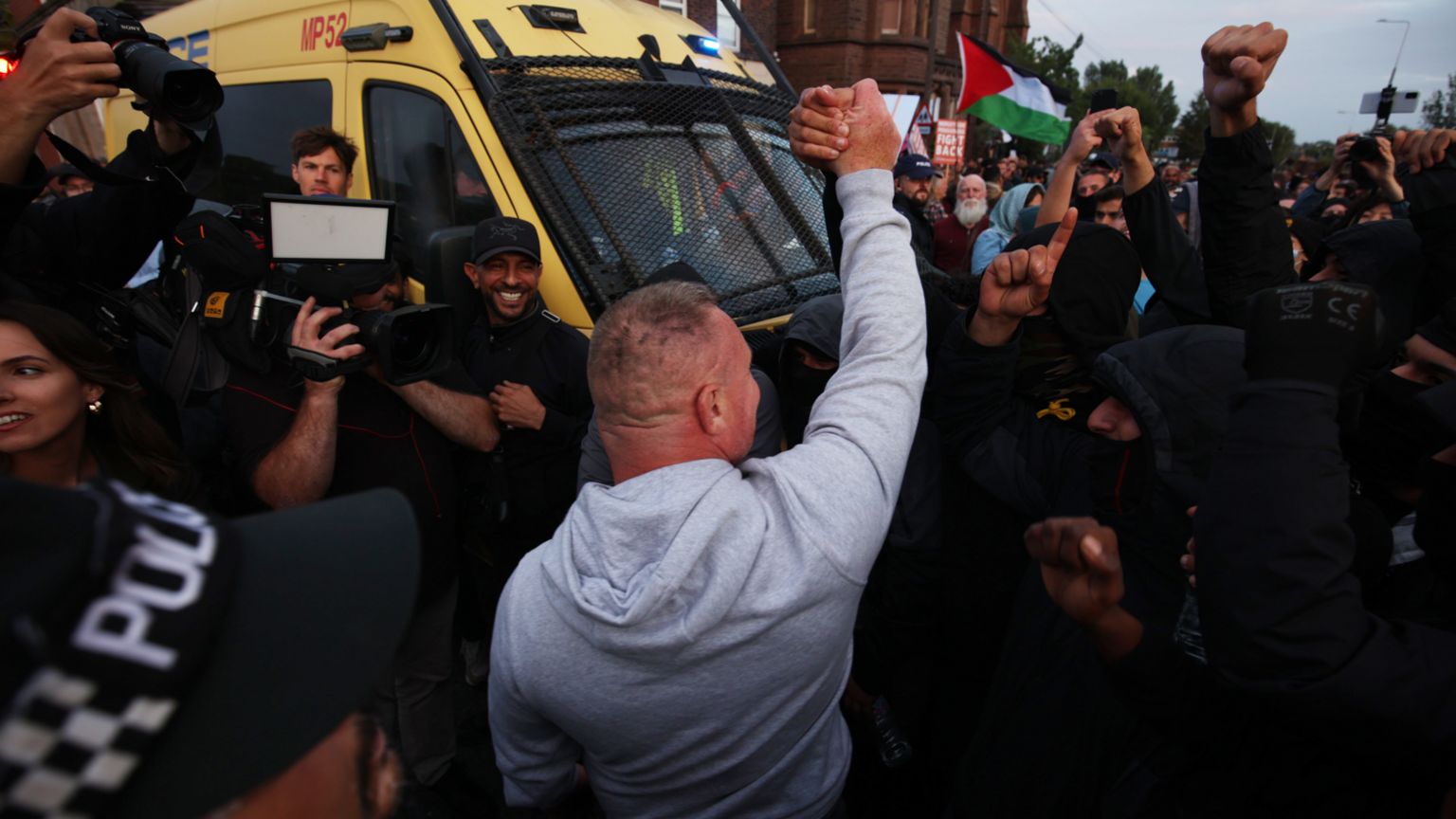 A man who reportedly said to the protesters he was on neither side of the protests, but agreed with some of the issues on both sides, gestures to the crowds and is cheered on