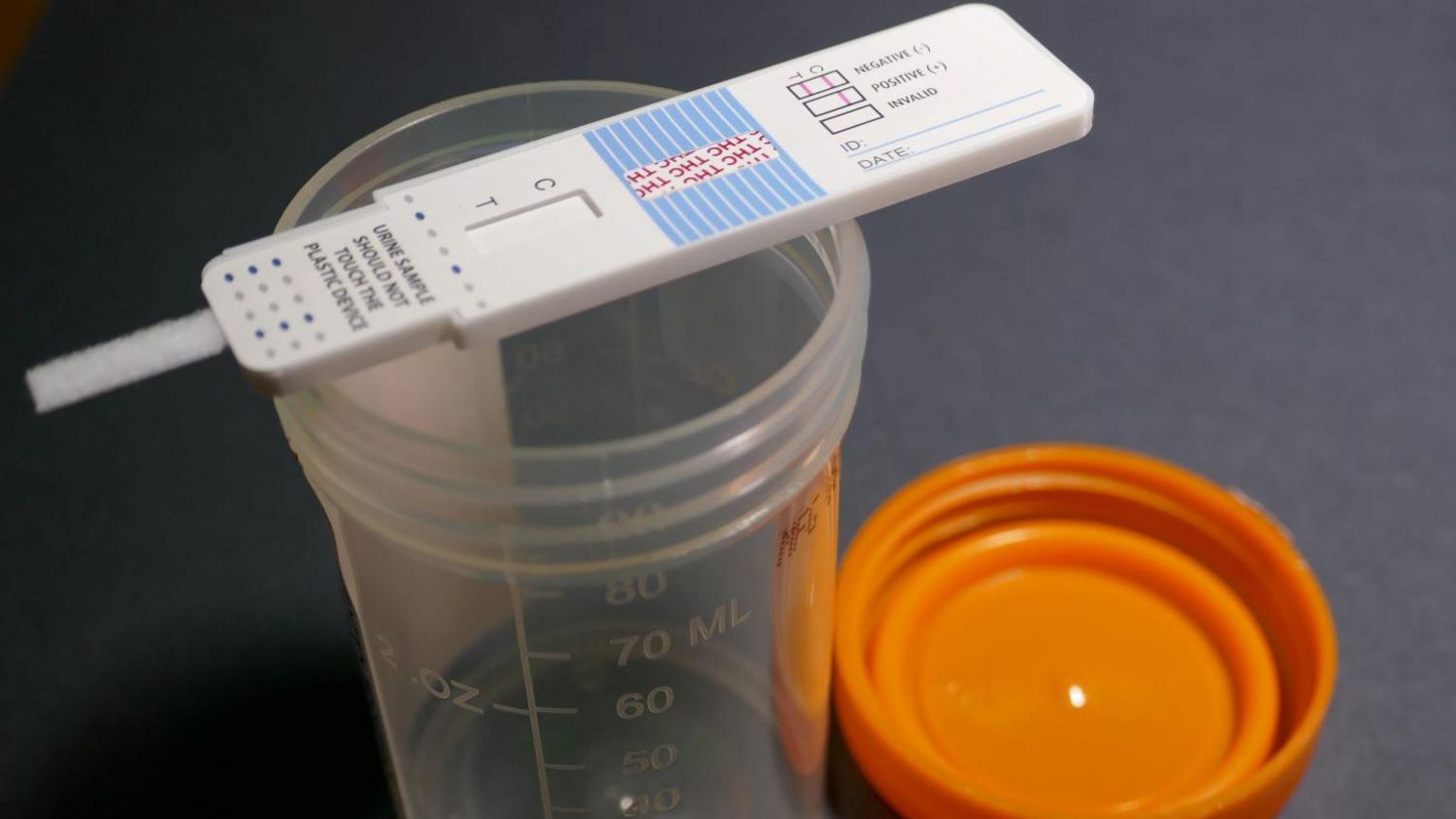 A drug test on top of an empty urine sample bottle