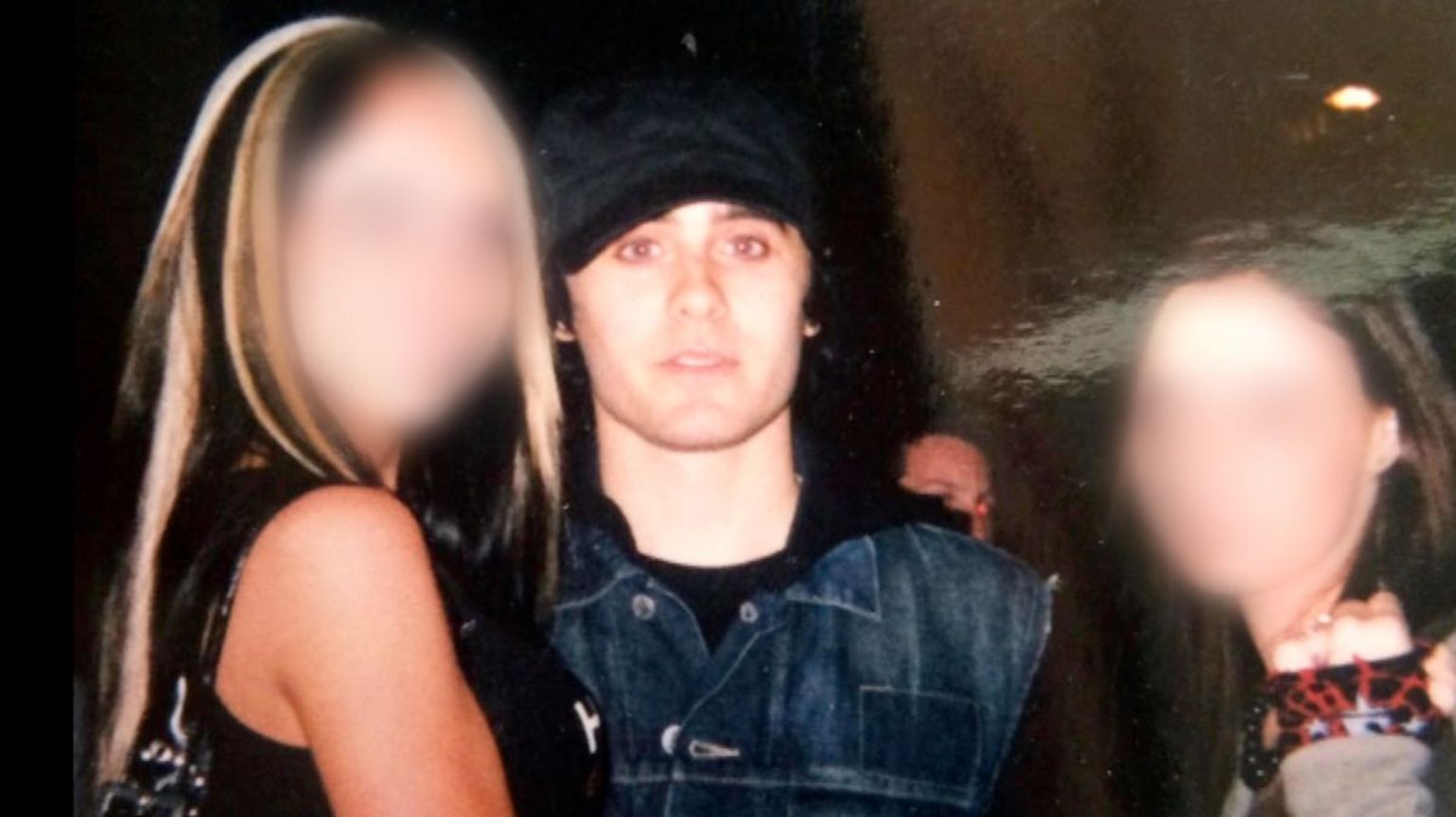 杰瑞德·莱托（Jared Leto）穿着牛仔夹克，戴着黑色帽子，直视镜头。他与两个年轻女孩合影。女孩脸部经模糊，左边是金发女孩，比莱托高一点，右边是一个矮一点的黑发女孩。在黑暗的房间里，他们的脸被闪光灯照亮。