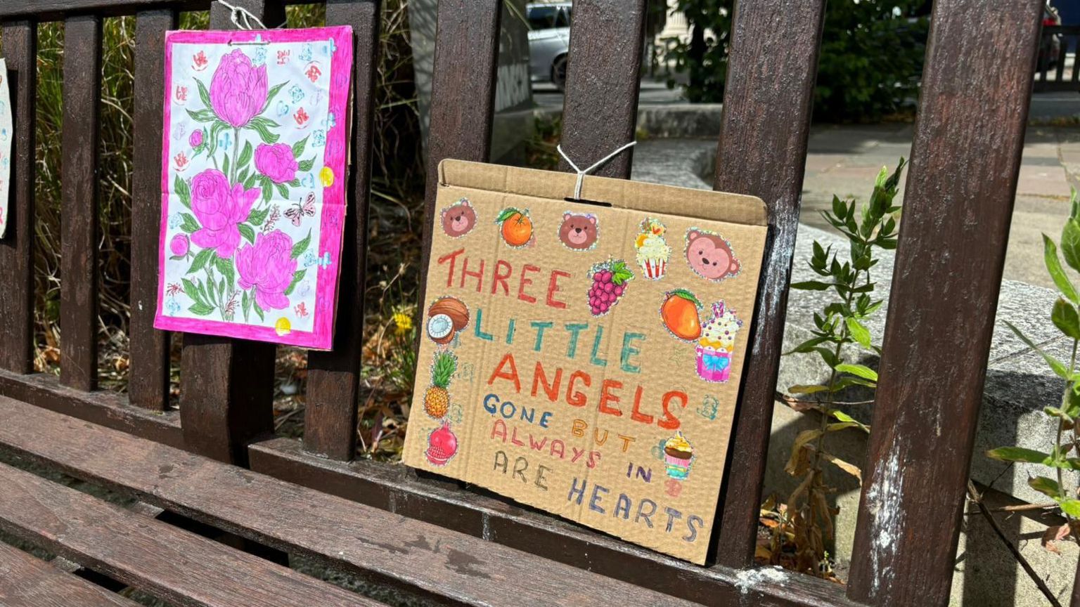 A sign on a bench which reads 'Three Little Angels, gone but always in are hearts"