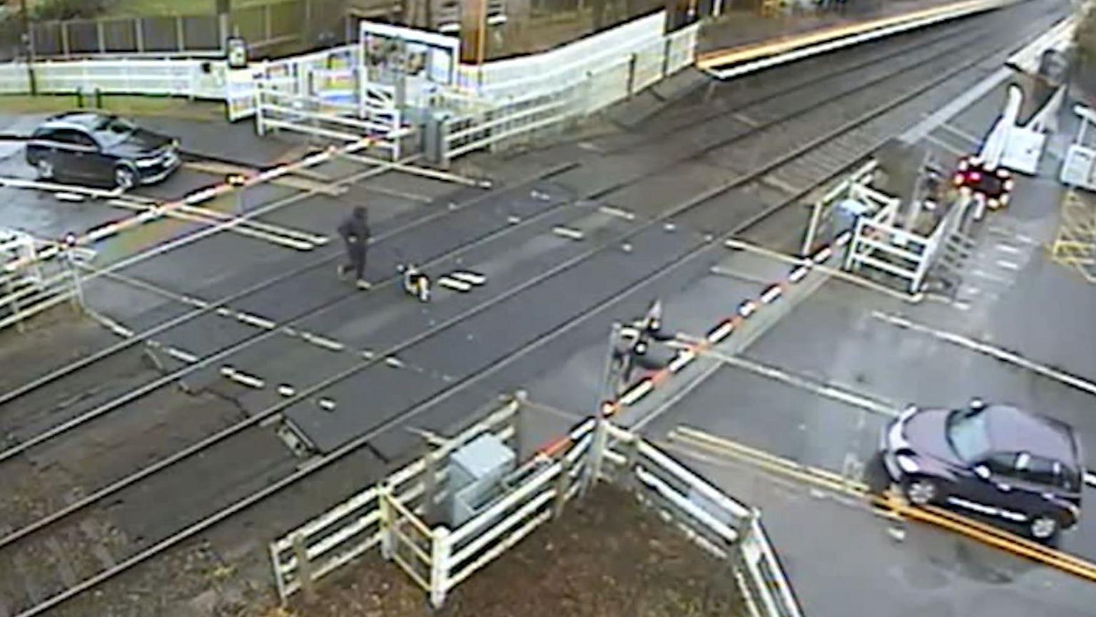 Screengrab of dog walker on level crossing