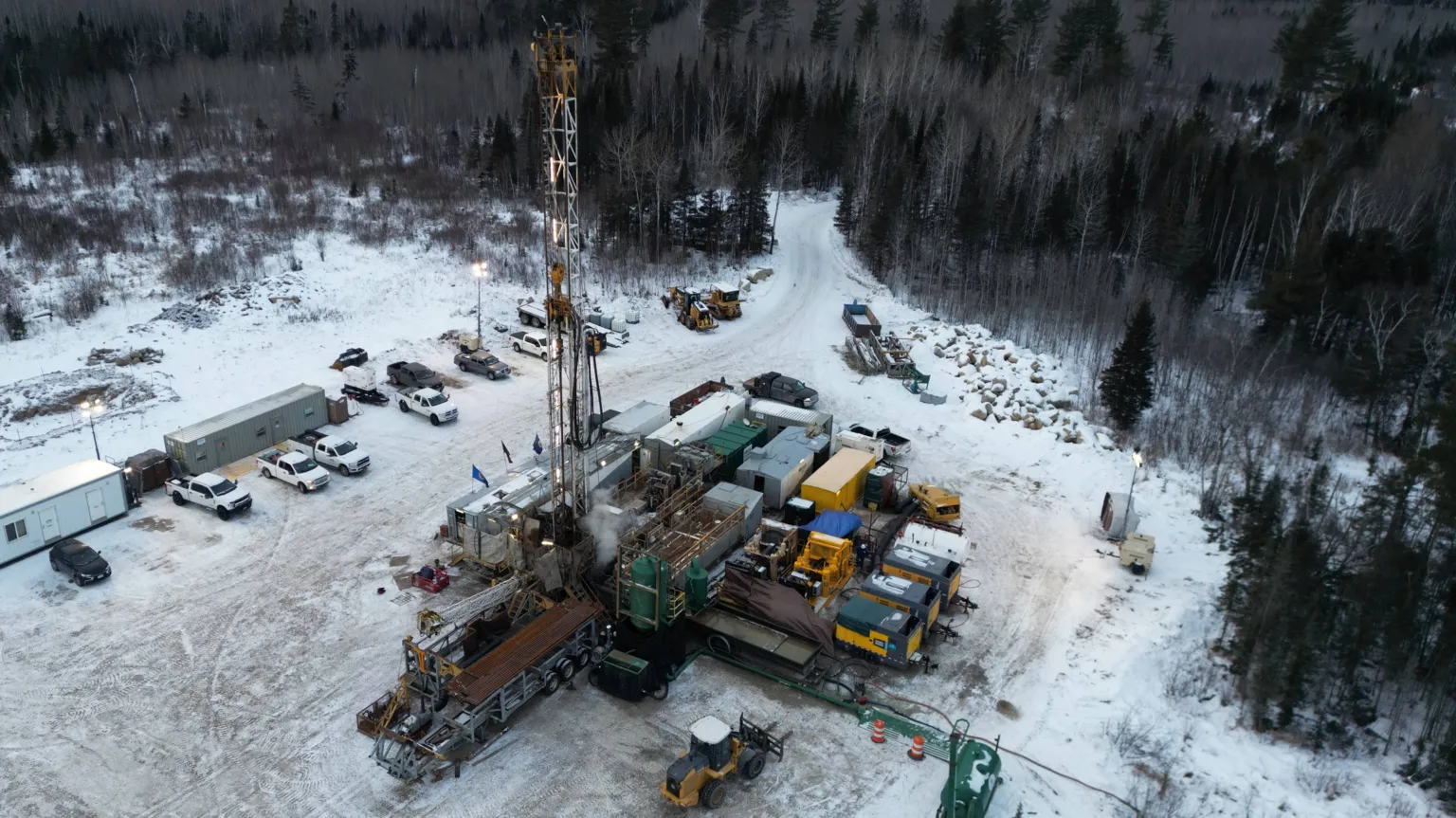 Pulsar Helium A drilling rig surrounded by snow, woods and industrial buildings and equipment