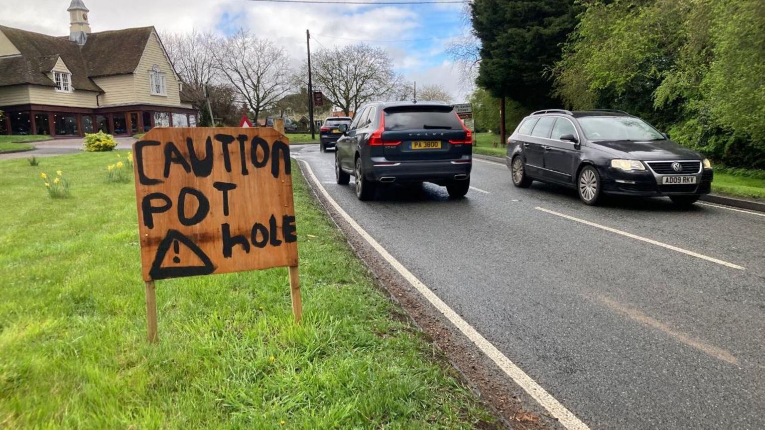 The sign reads 'caution pothole' on the side of the road to make drivers aware potholes are on the road